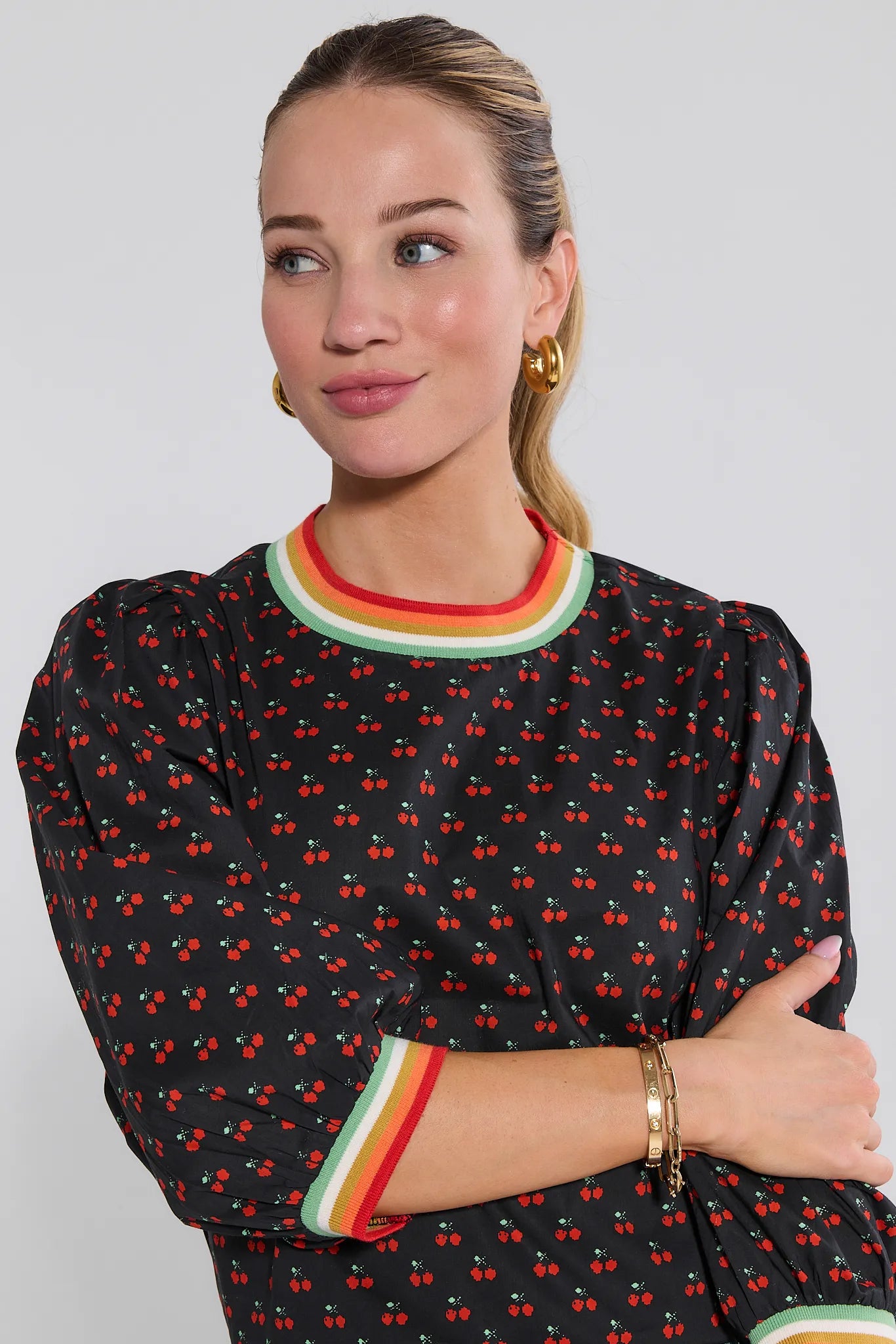 Woman wearing a Bailey Top
with red cherry pattern and colorful trim on a plain background