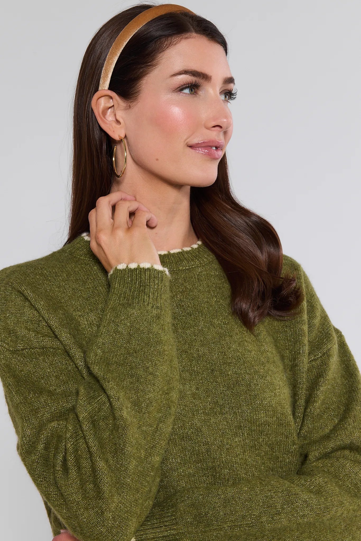 Woman wearing a olive Lottie Sweater with a plain background