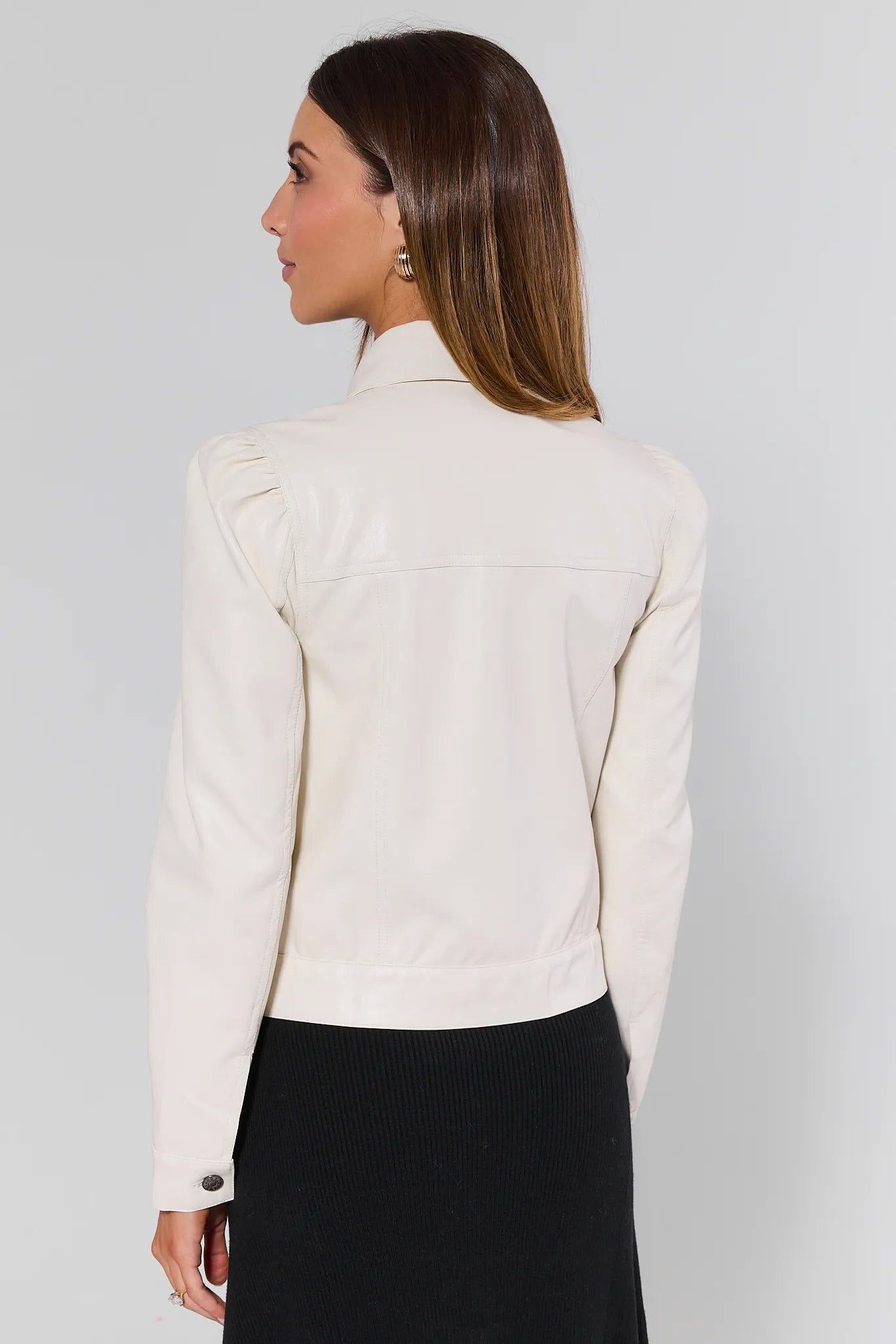 Woman wearing a Roxanna Cream Faux Leather Jacket over a black top on a plain background