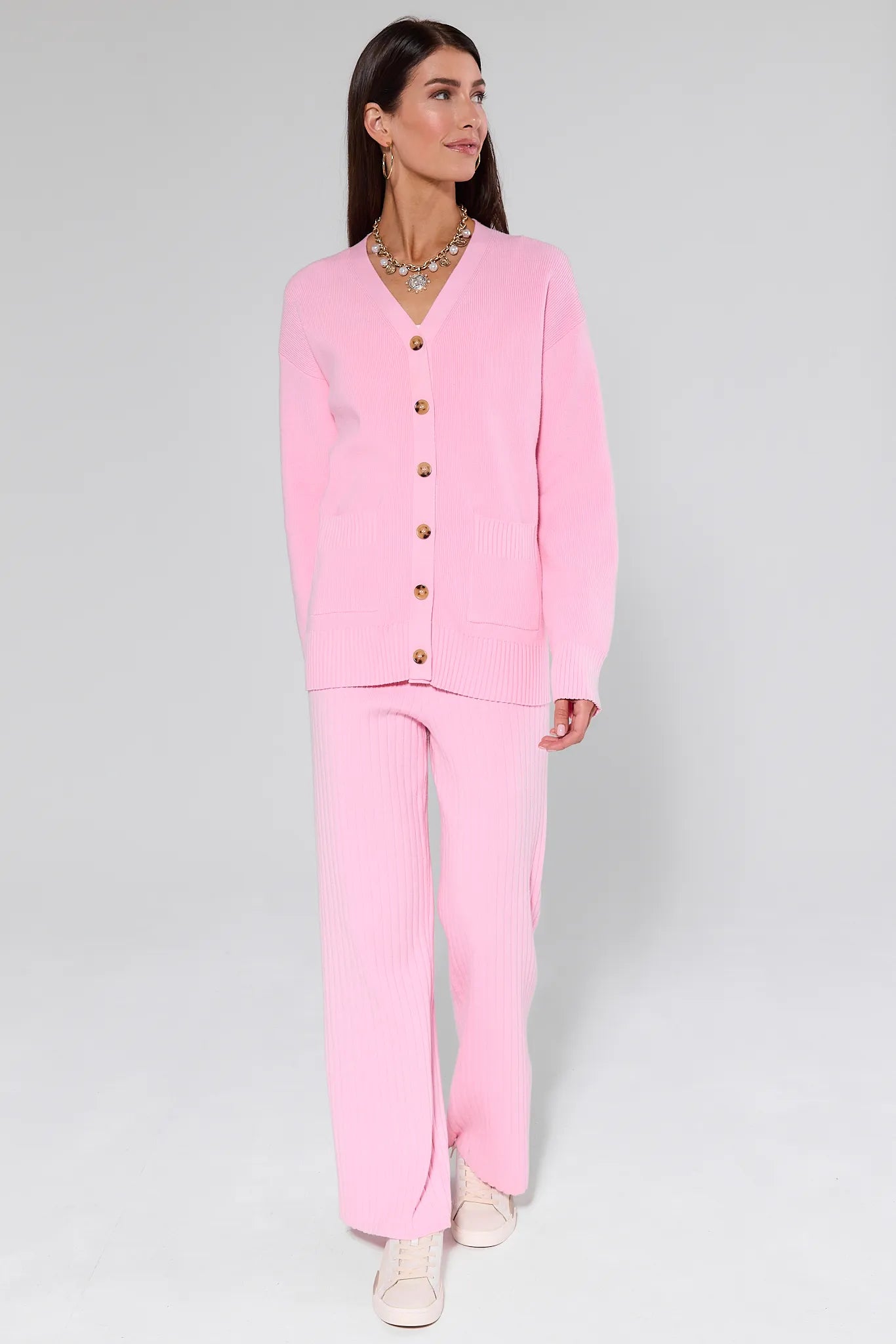 Woman wearing a Brianna Pink Knit Cardigan with gold buttons on a gray background