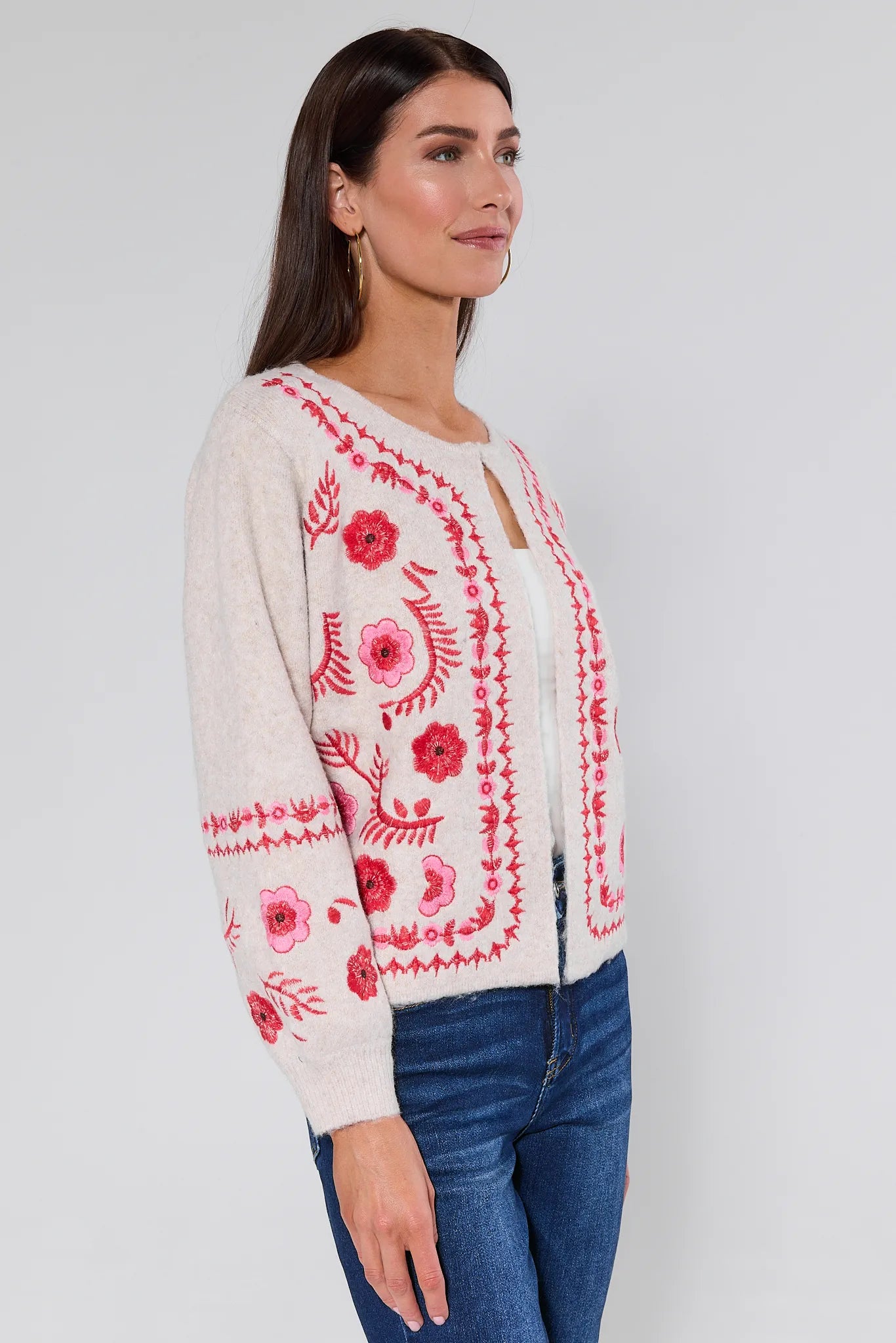Woman wearing a Hallie Embroidered Knit Cardigan with red floral embroidery on a plain background