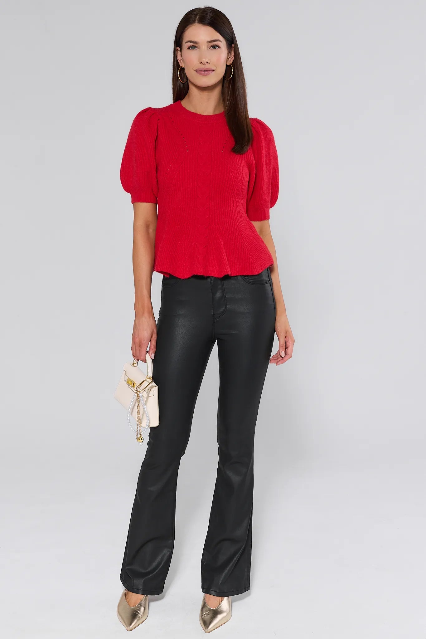 Woman wearing a red hillary sweater with puff sleeves against a plain background