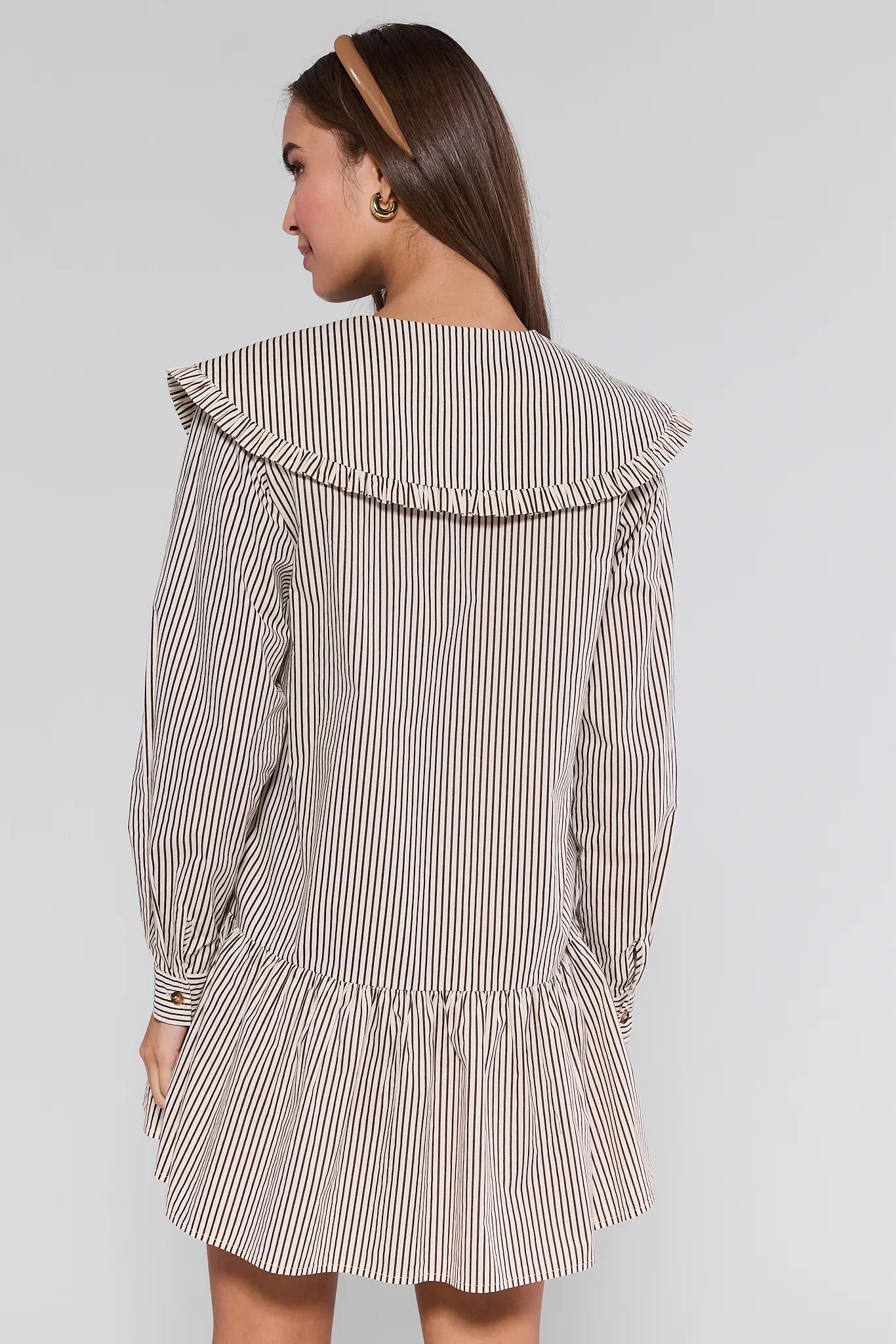 Woman wearing a striped Berkley Dress with a ruffled collar on a plain background