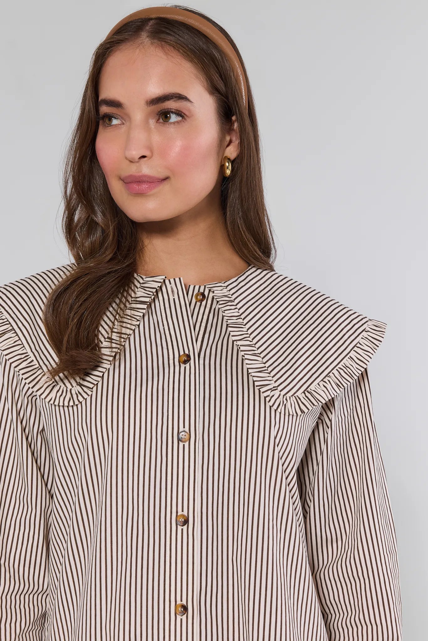 Woman wearing a striped Berkley Dress with ruffled shoulders against a plain background
