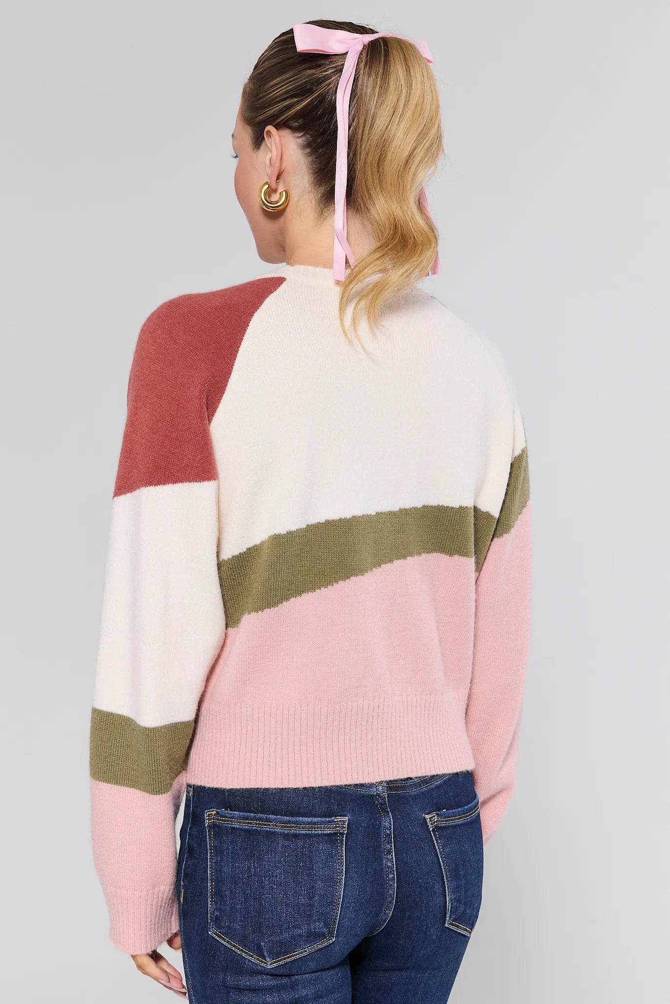 Person wearing a colorful striped Beverly Sweater with a plain background