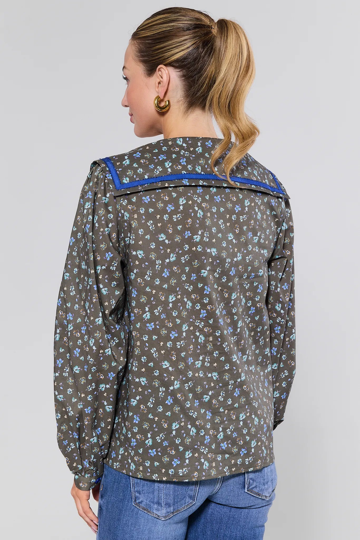 Woman wearing a patterned Carol Top
with blue accents on a plain background