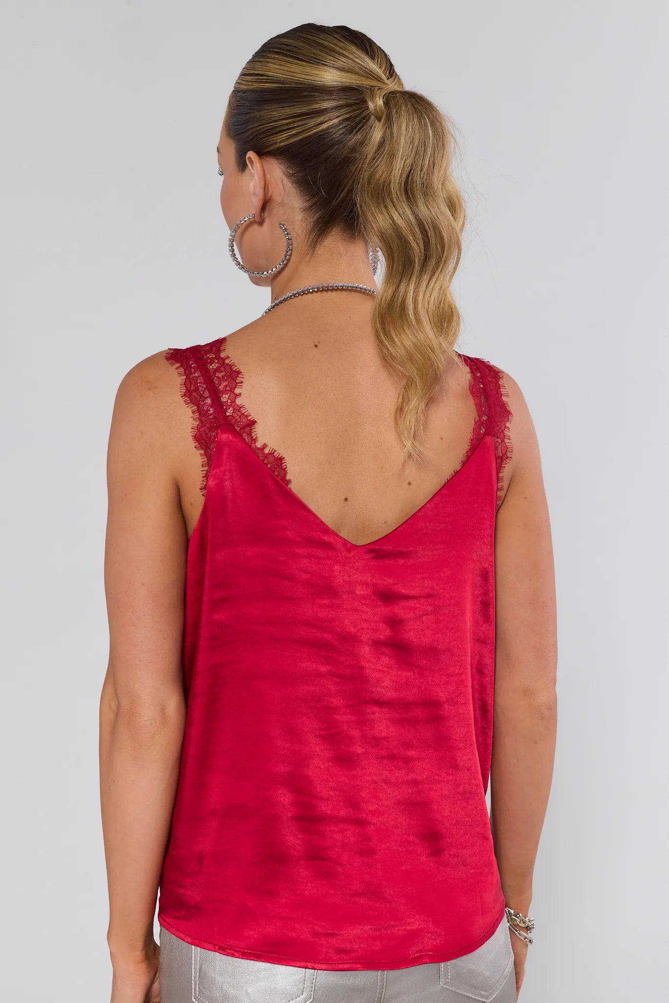 Woman wearing a red sleeveless top with lace details on a white background