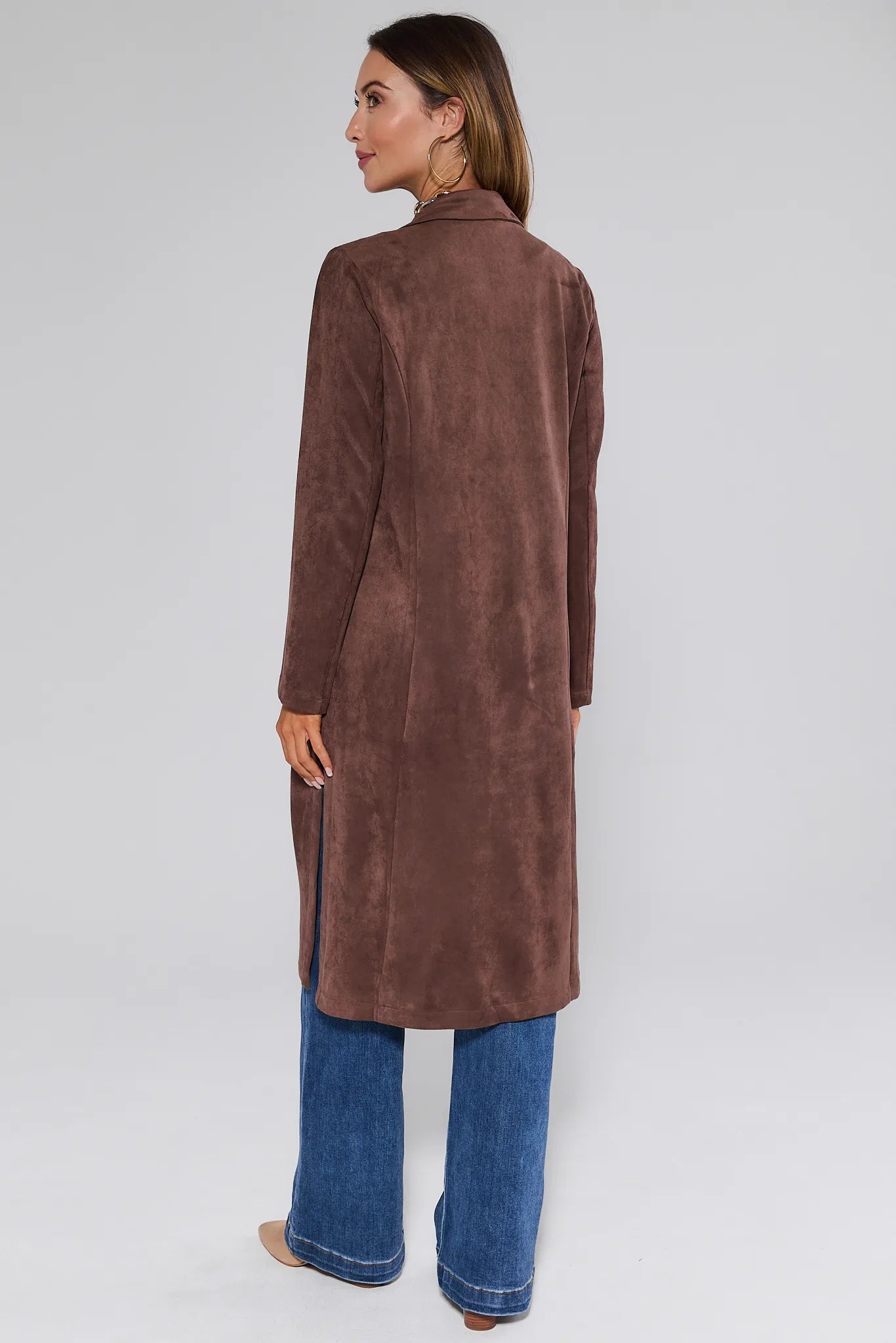 Woman wearing a brown suede Nadine Coat and blue jeans on a white background