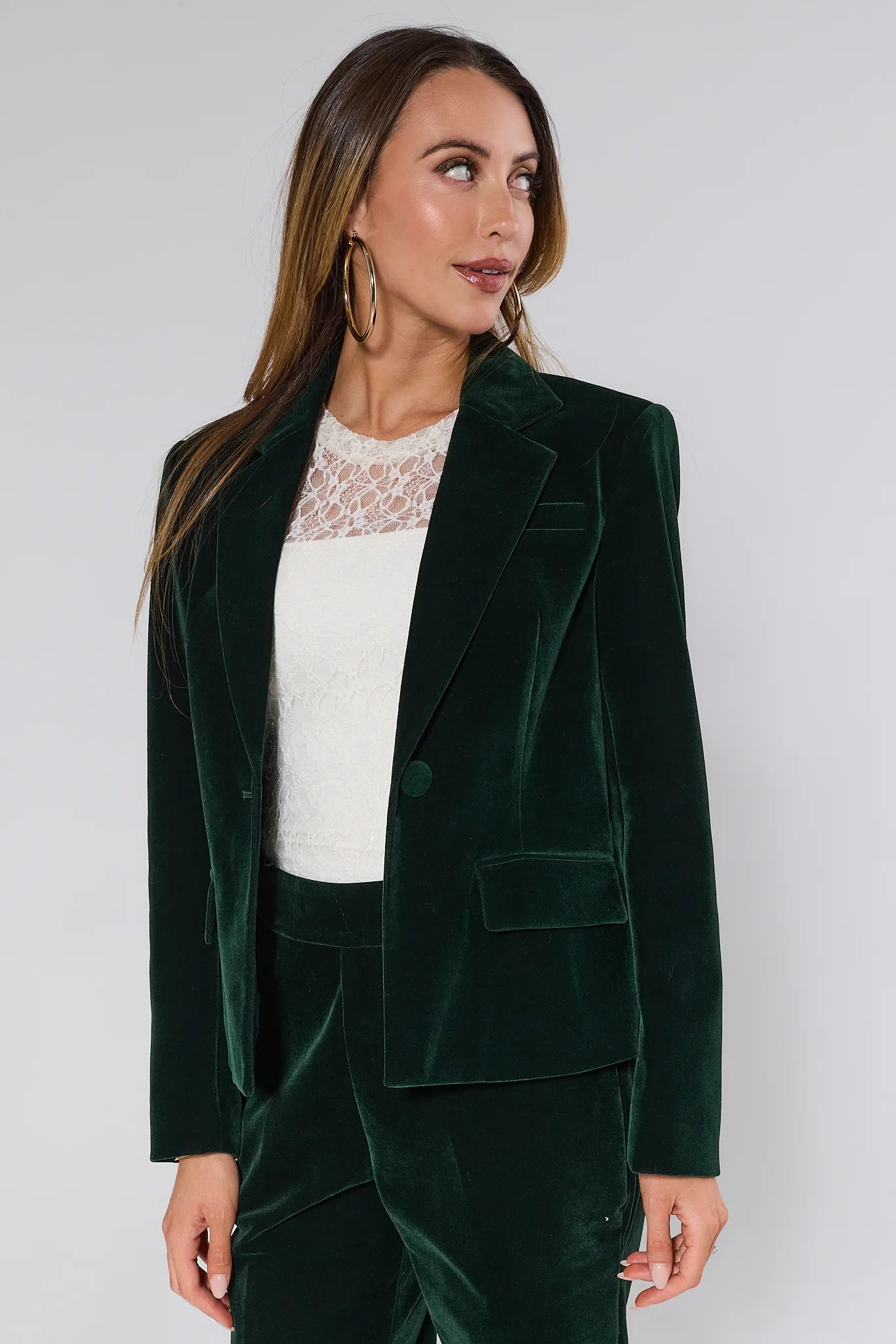 Woman wearing a green velvet evie blazer and pants against a white background