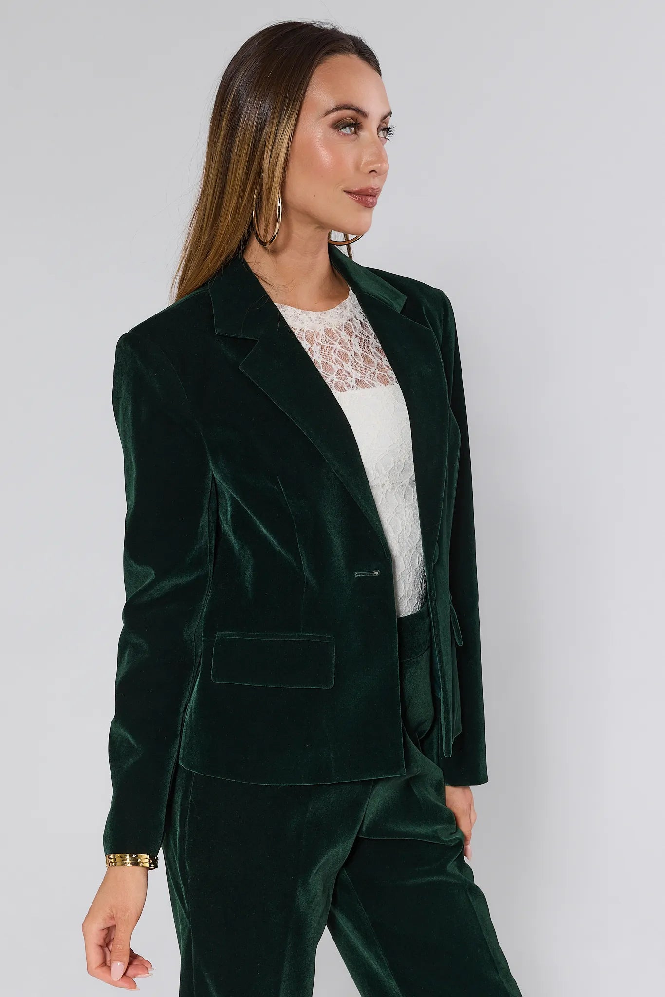 Woman wearing a green velvet evie blazer and pants against a white background