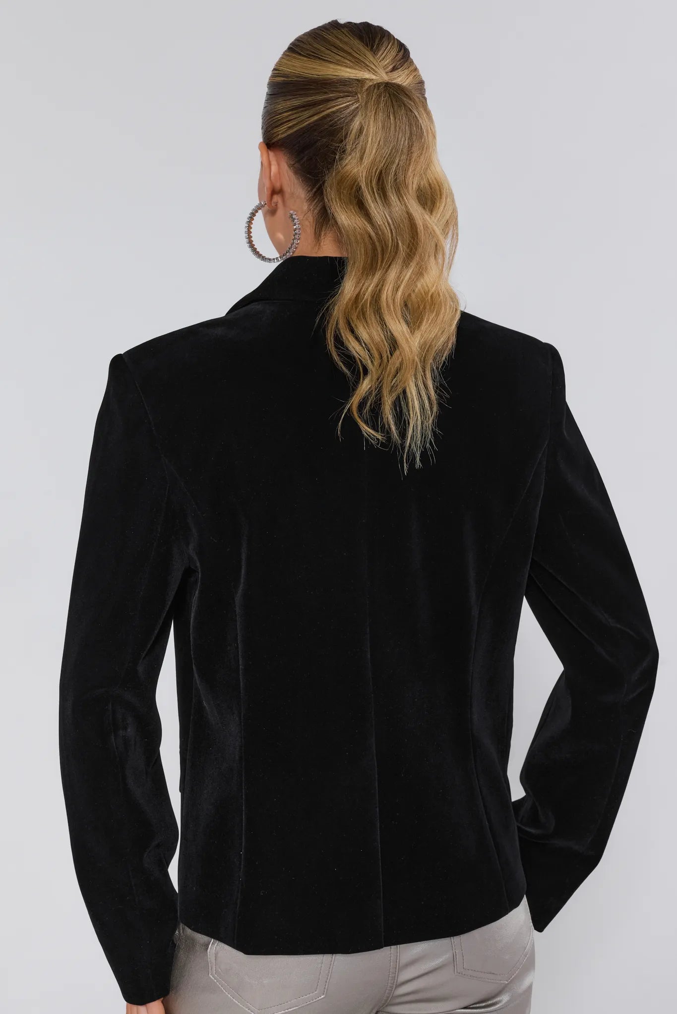 Black velvet blazer worn by a person on a white background