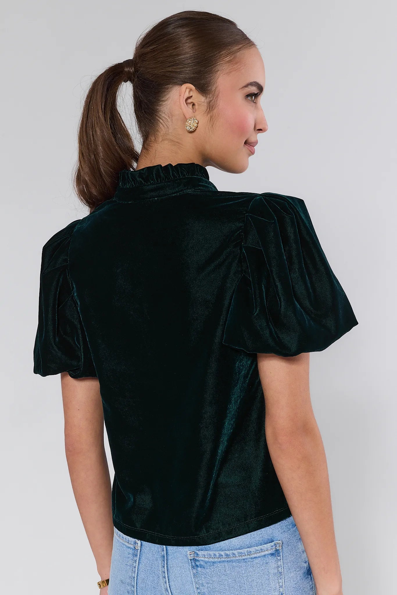 Woman wearing a Lynette Green Velvet Puff Sleeve Top against a plain background