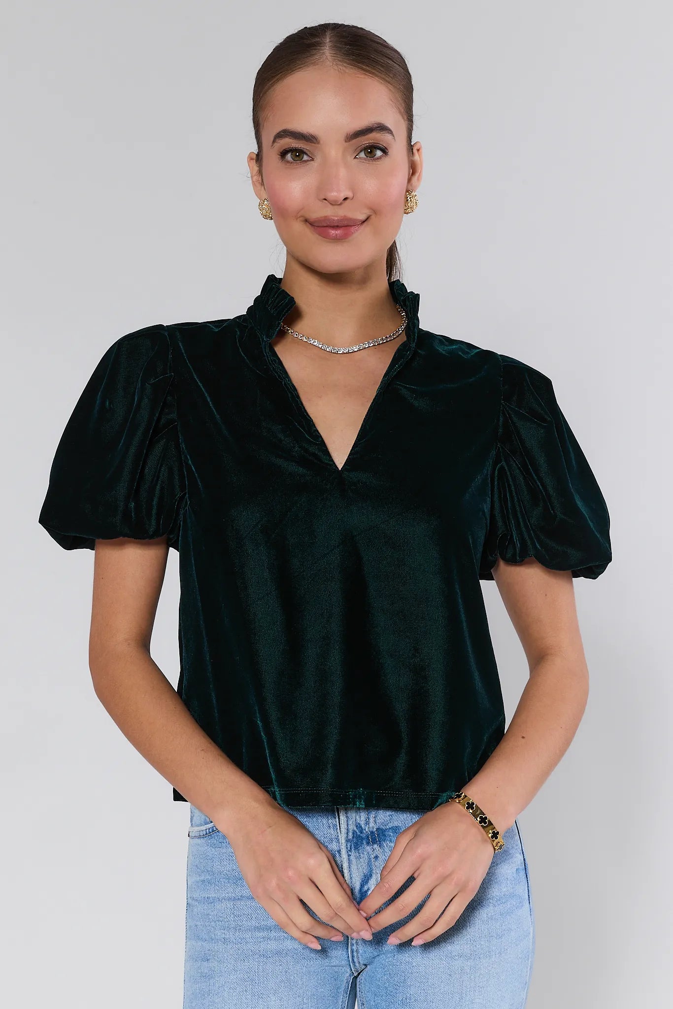 Woman wearing a Lynette Green Velvet Puff Sleeve Top against a plain background