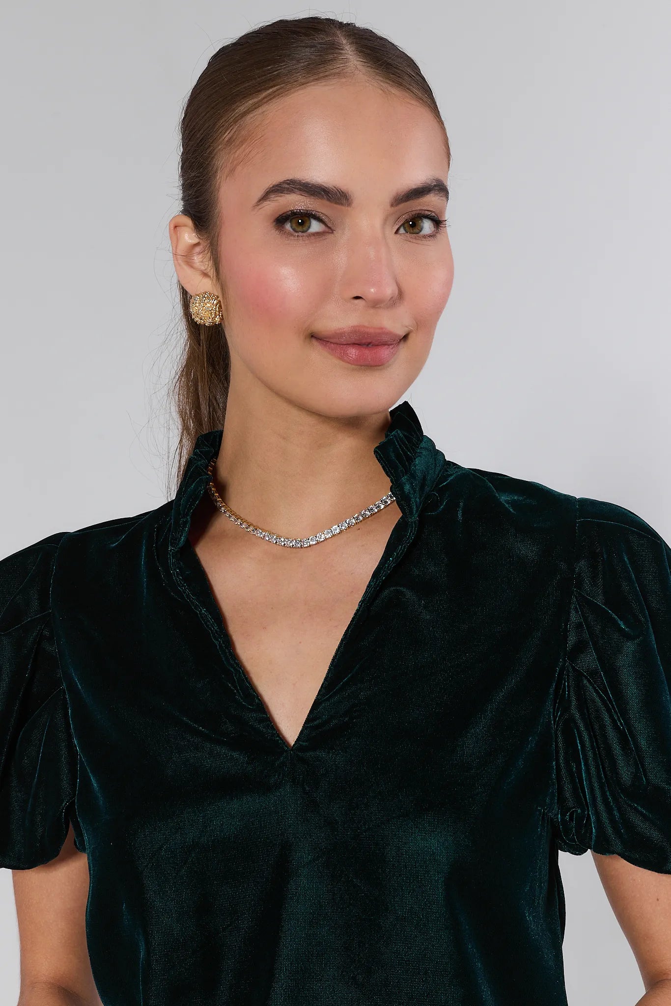 Woman wearing a Lynette Green Velvet Puff Sleeve Top against a plain background