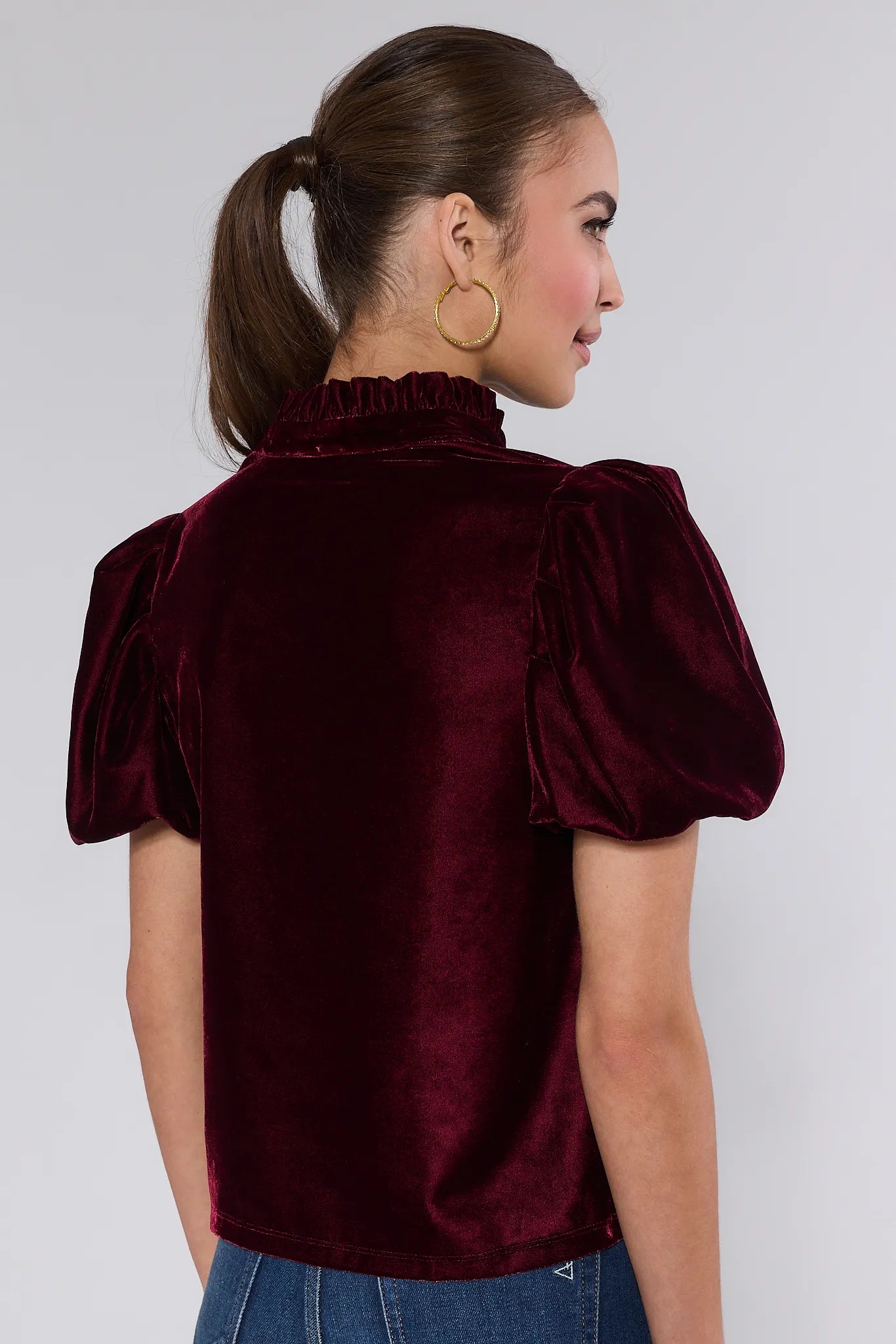 Woman wearing a Lynette Cranberry Velvet Puff Sleeve Top against a plain background