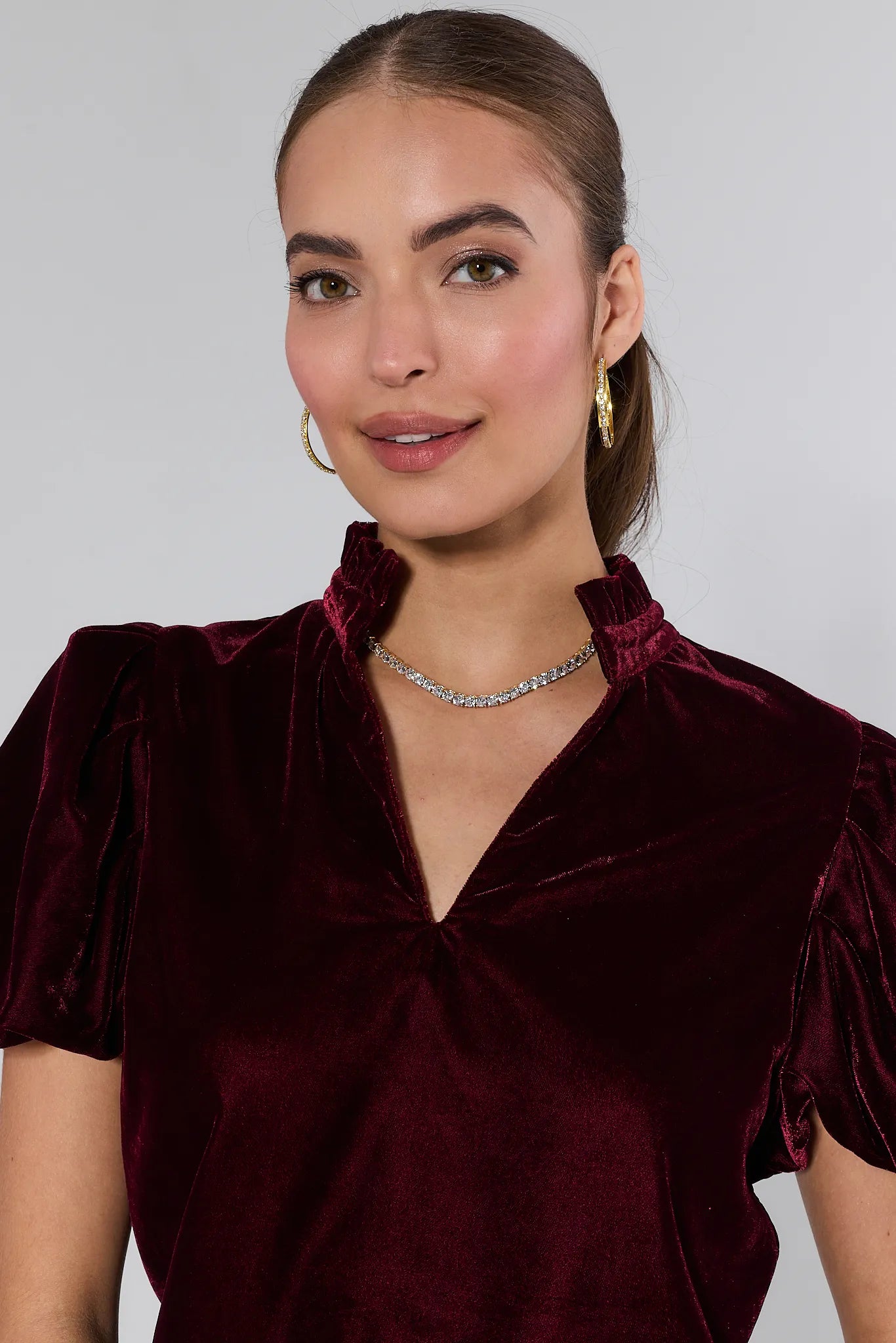 Woman wearing a Lynette Cranberry Velvet Puff Sleeve Top against a plain background