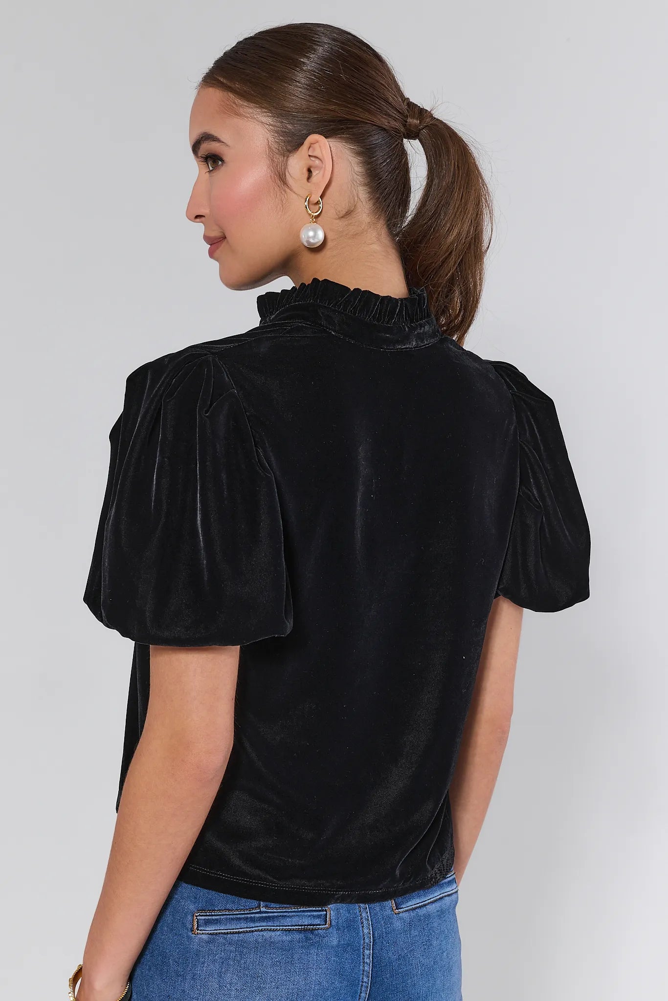 Woman wearing a Lynette Black Velvet Puff Sleeve Top against a plain background