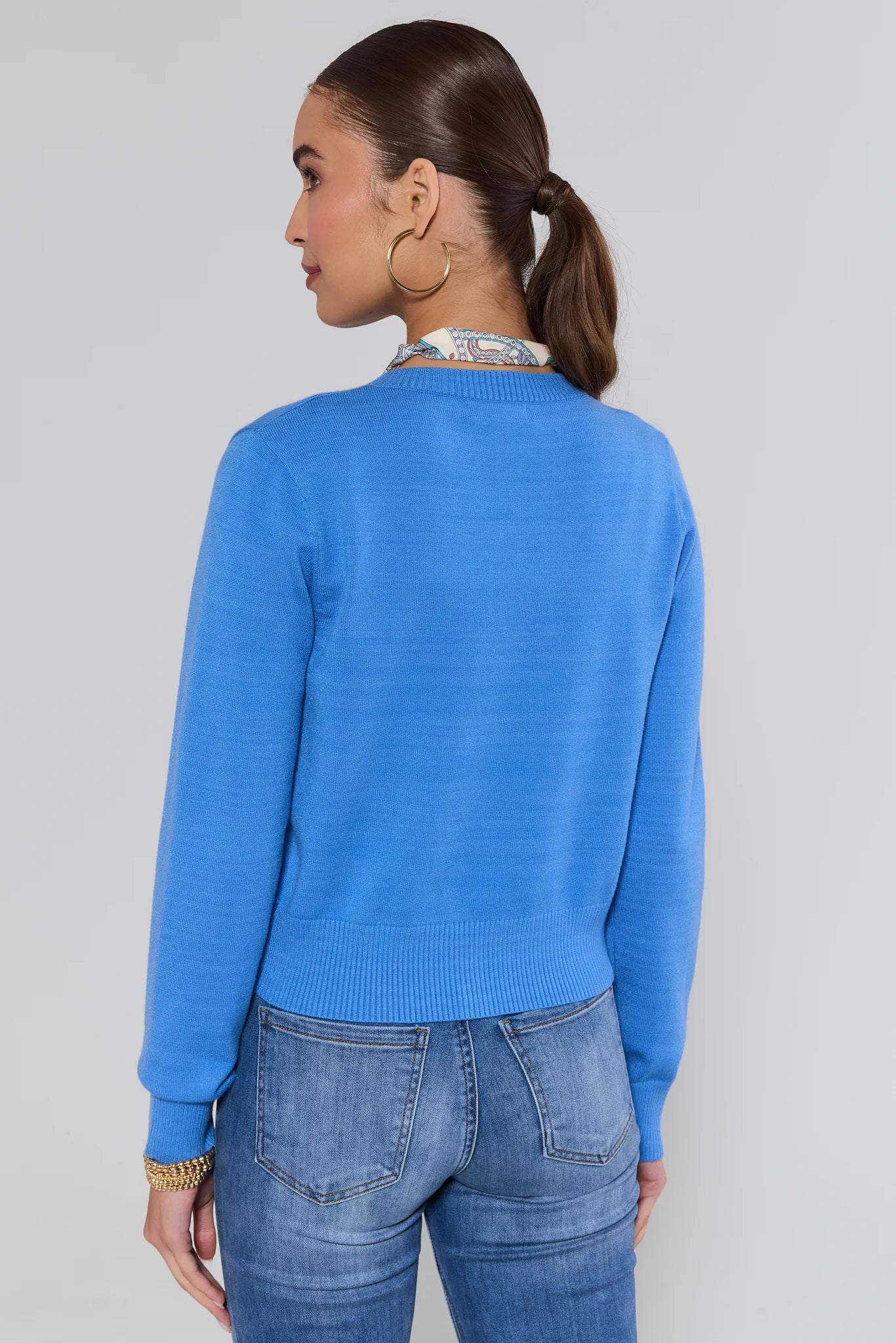 Woman wearing a Sarah Blue Button Up Cardigan and jeans on a plain background