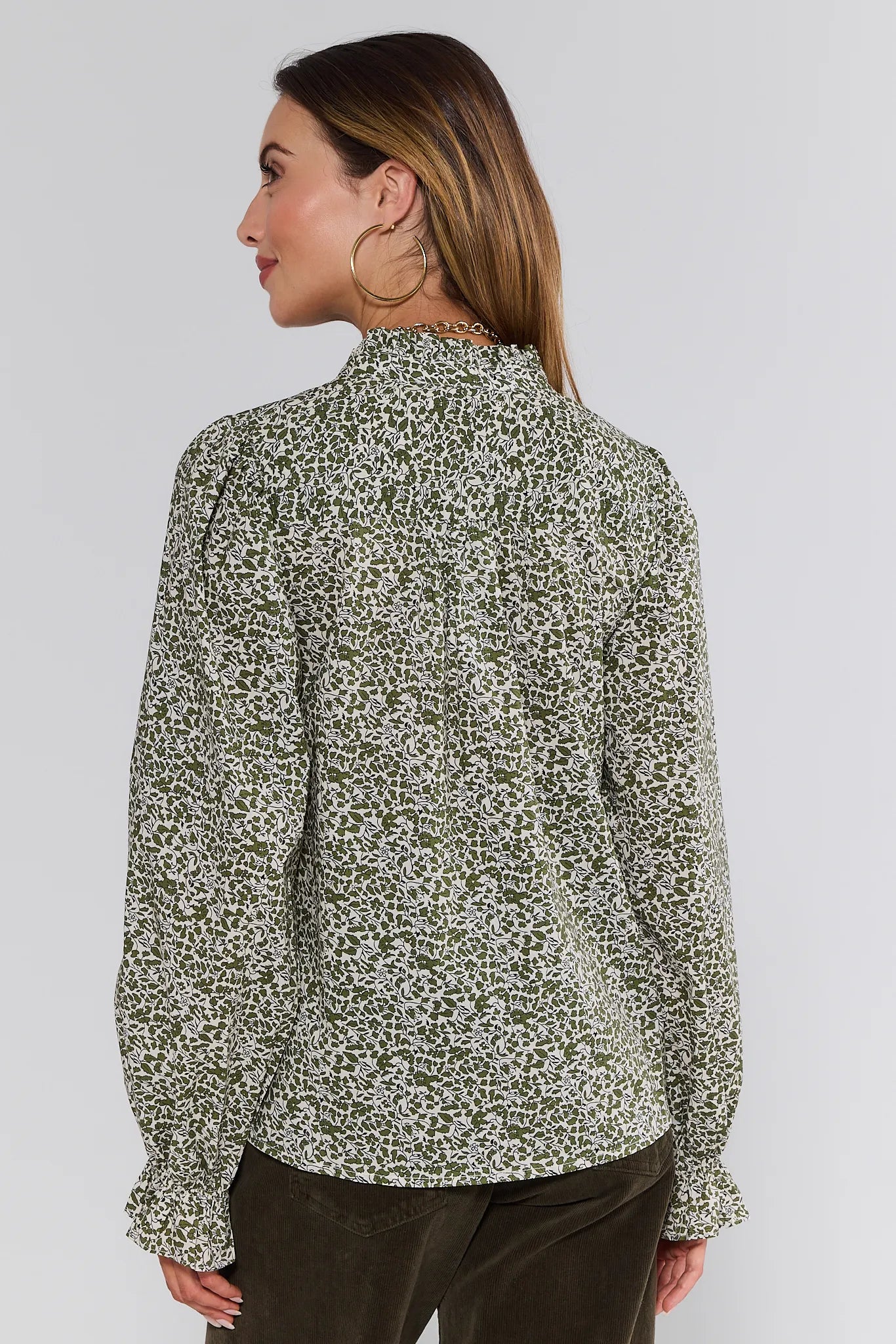 Woman wearing a floral Mitzi Top against a plain background