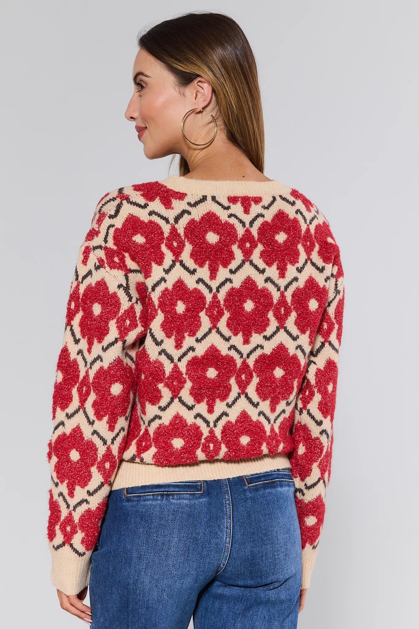 Woman wearing a red floral patterned Brynn Sweater with a plain background