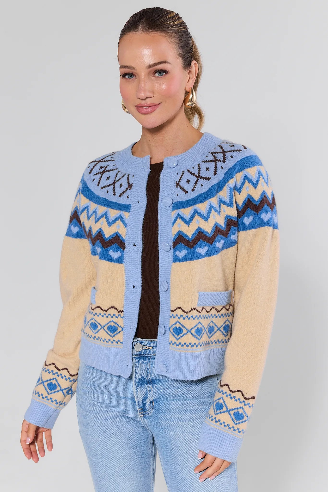 Woman wearing a blue and beige patterned cardigan on a plain background