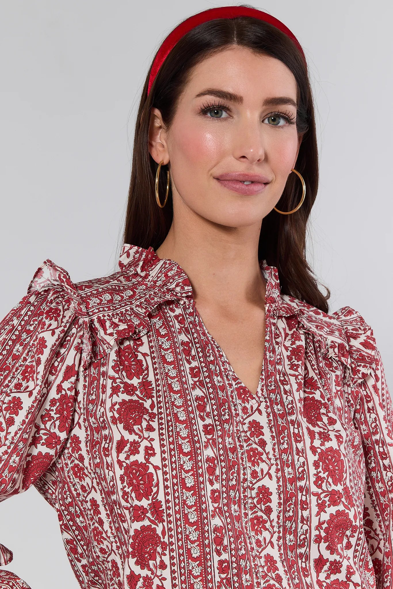 Woman wearing a red and white patterned Morgan Top with a plain background