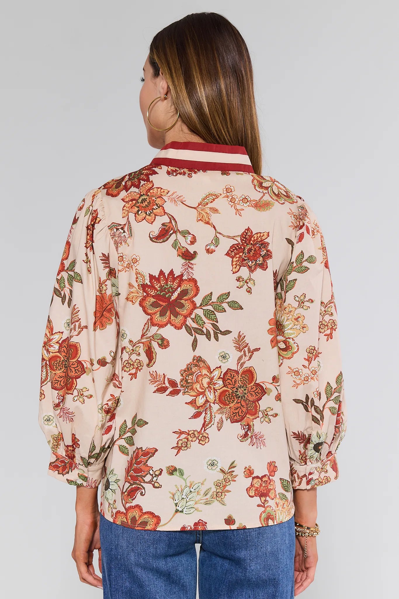 Woman wearing a floral Myra Top with a plain background