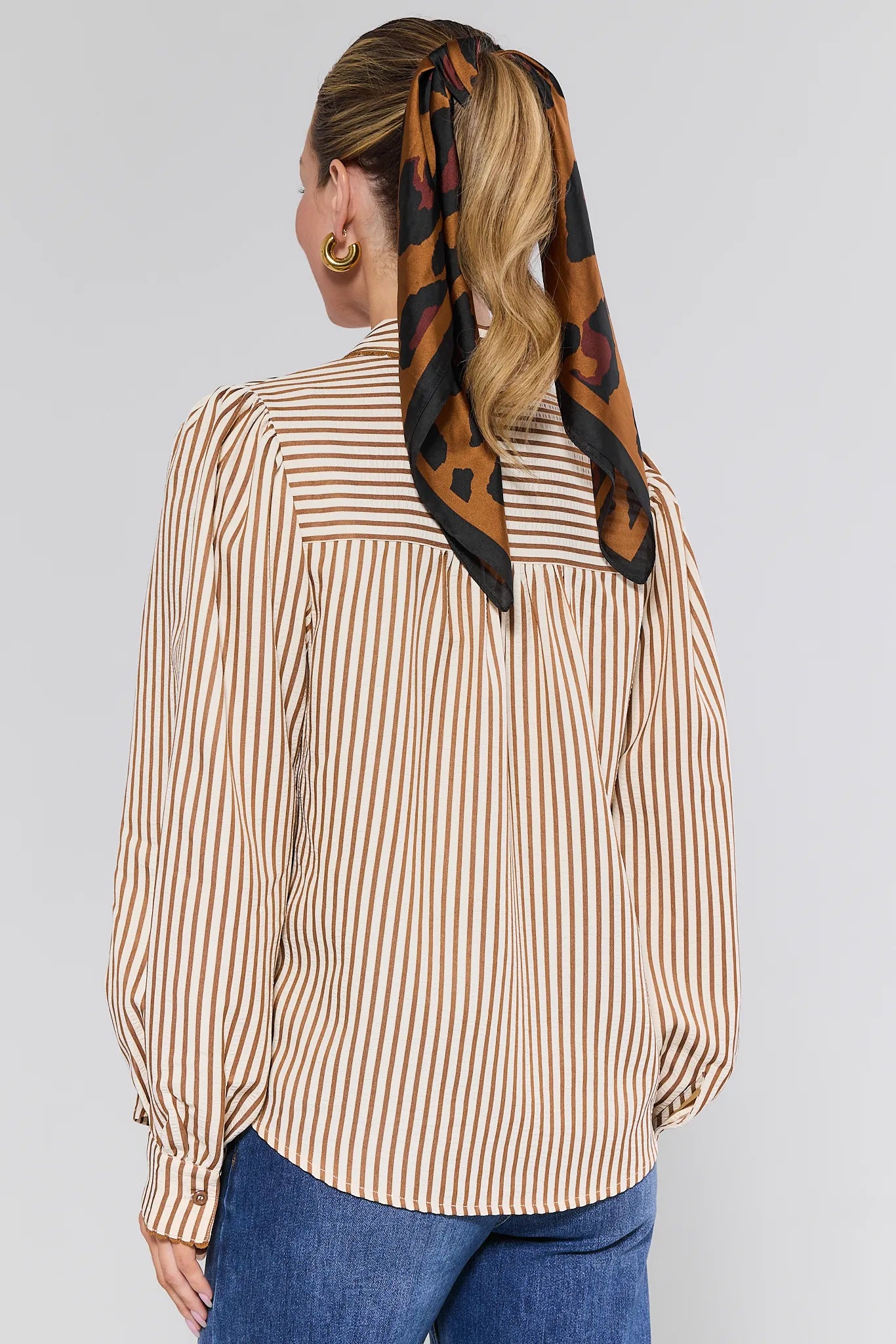 Woman wearing a striped Levi Top with a patterned scarf on her head against a plain background
