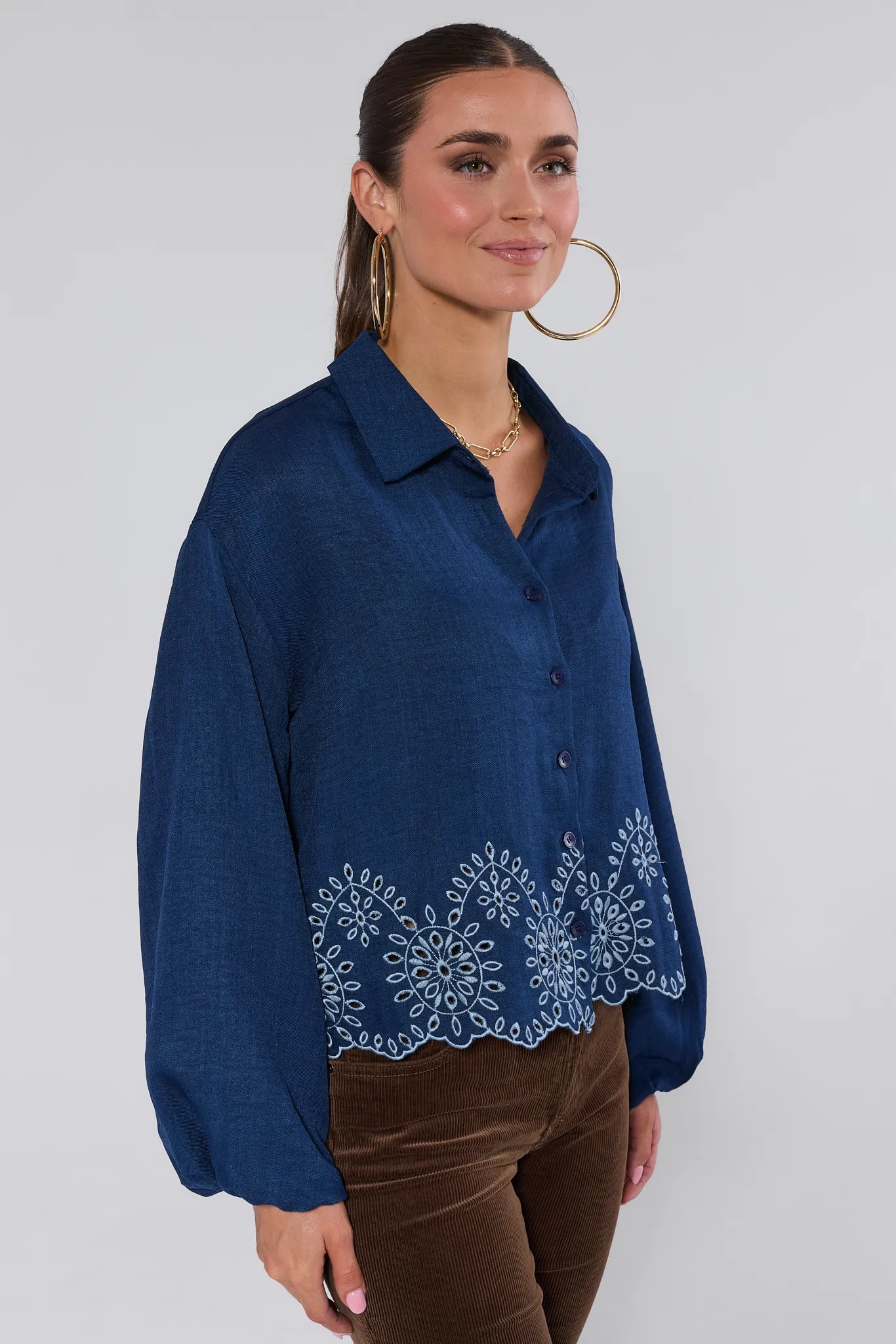 Woman wearing a blue embroidered Micah Top against a white background