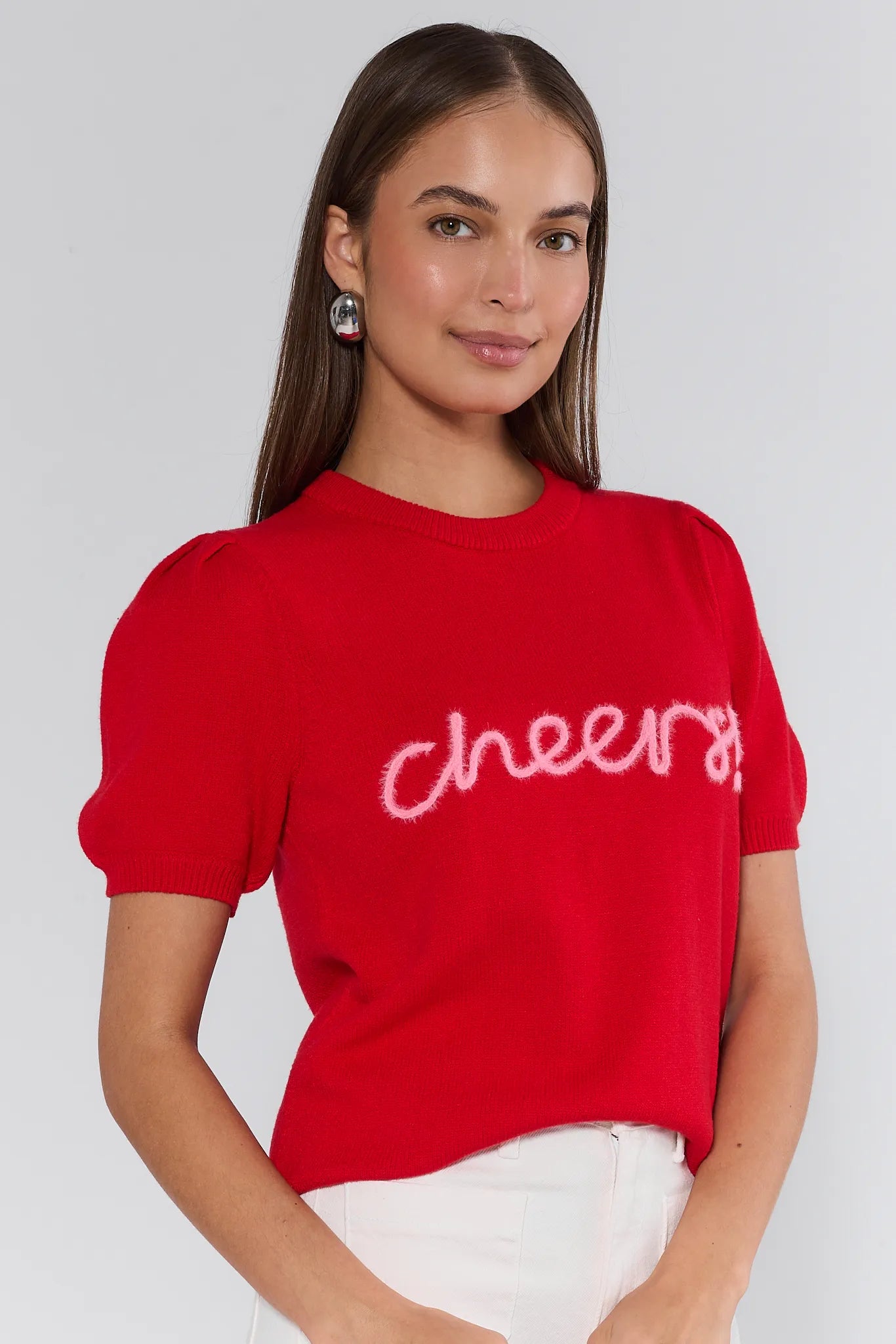 Woman wearing a red sweater with 'cheers' text on a plain background