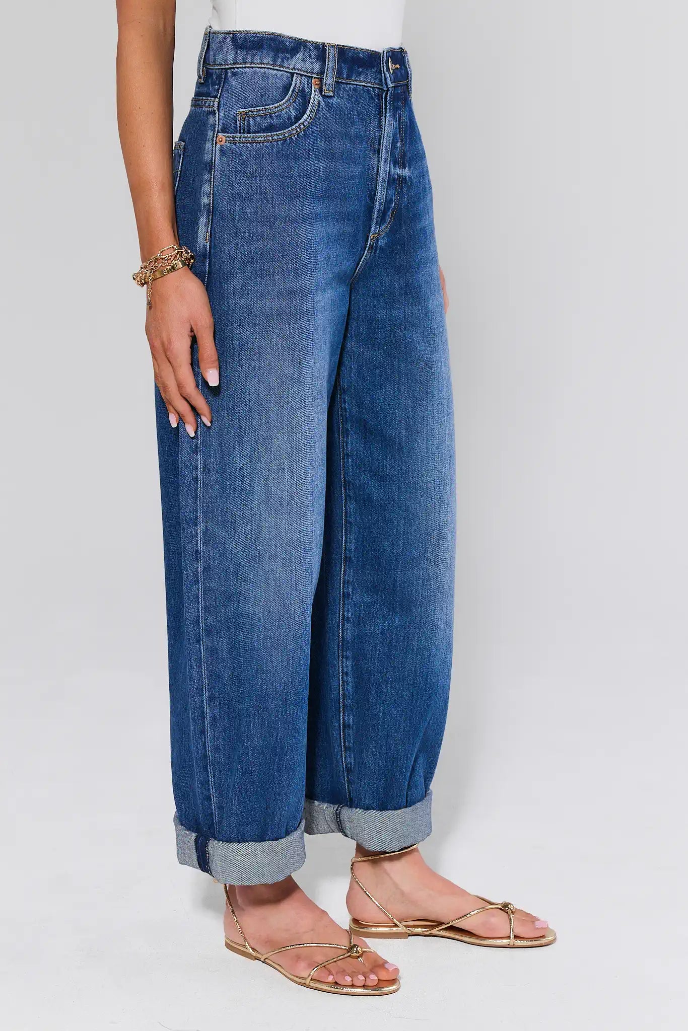 Person wearing blue jeans and sandals on a plain background