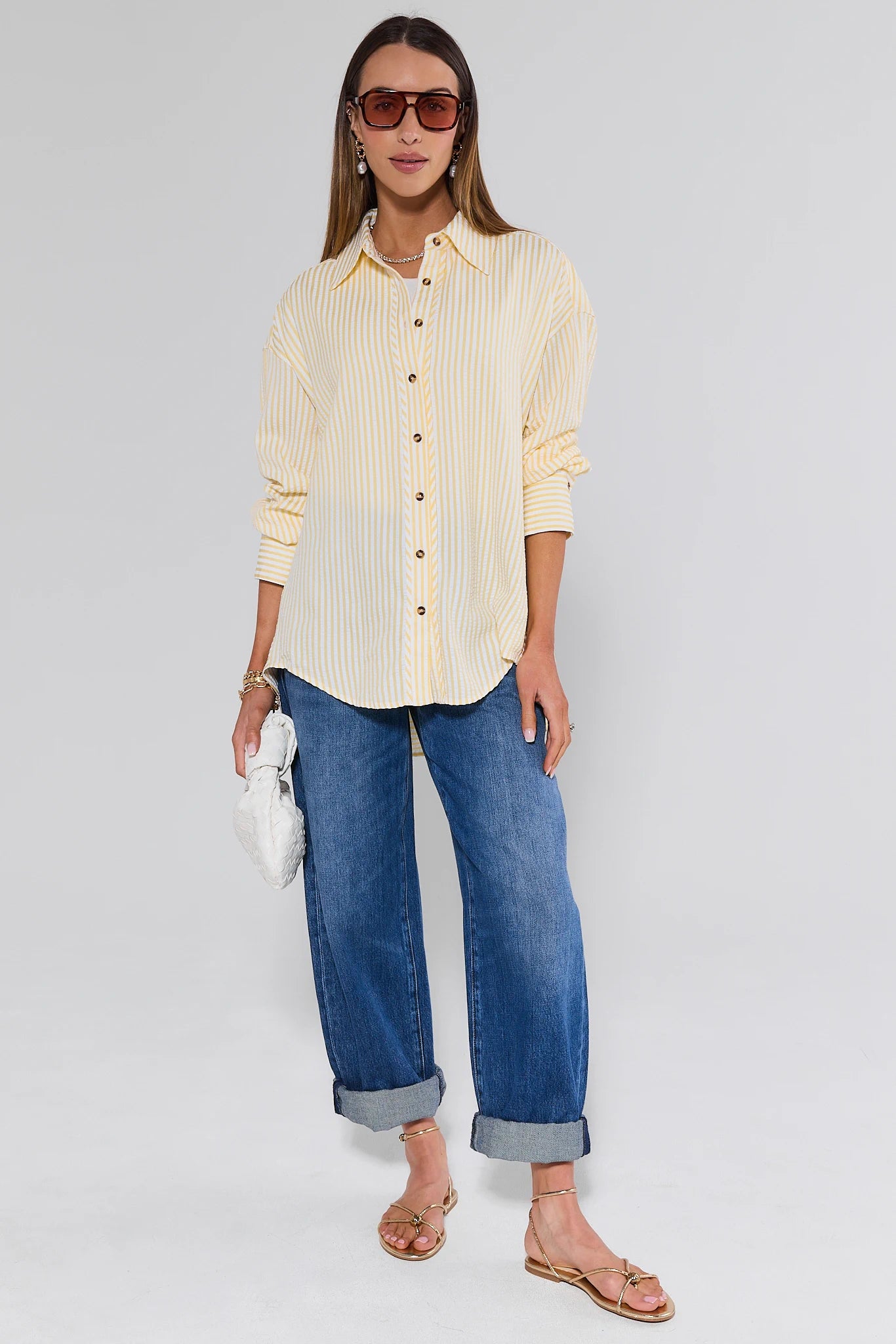 Woman wearing a yellow striped shirt and blue jeans on a white background