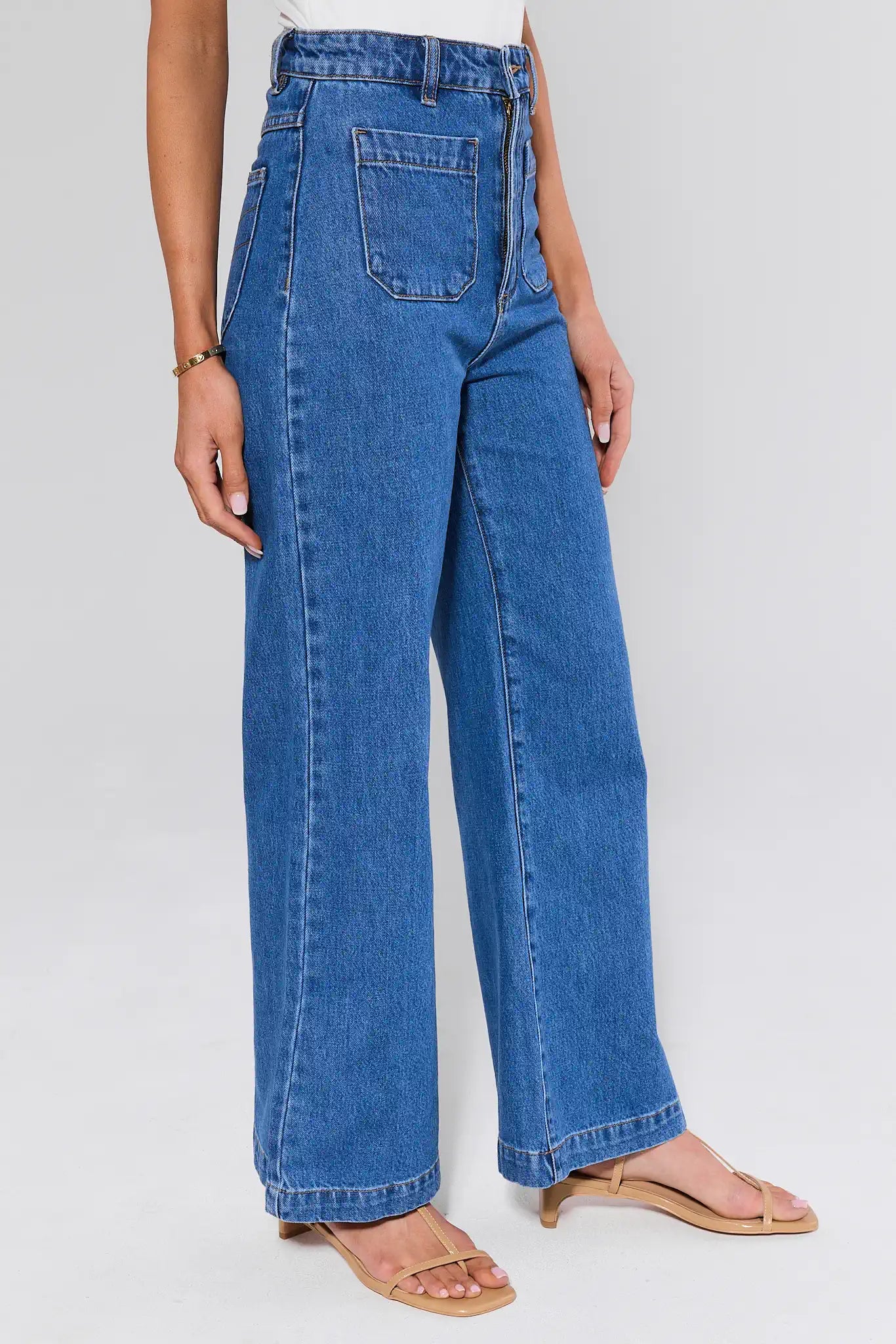 Person wearing blue jeans on a plain background