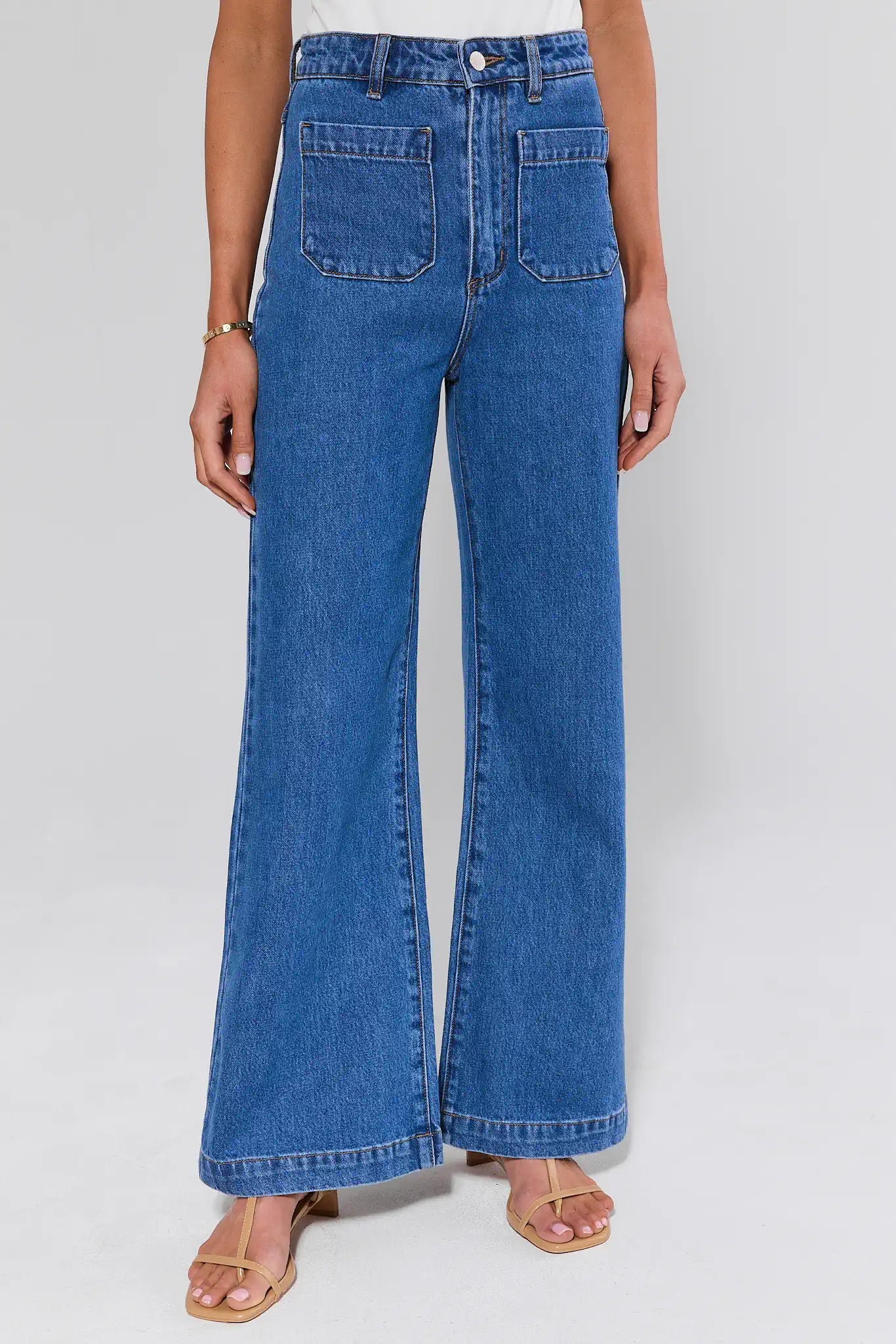 Person wearing blue jeans on a plain background