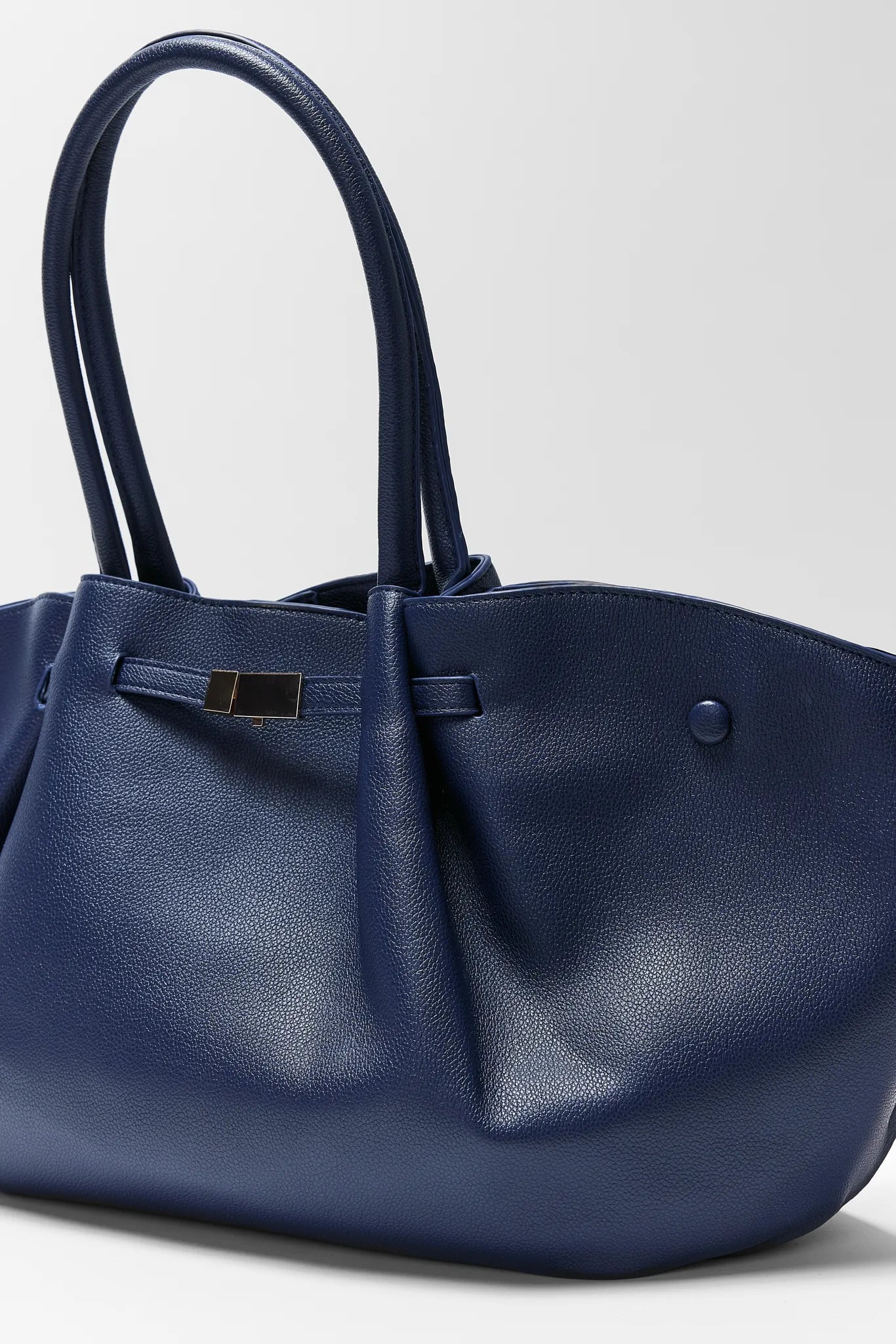 Blue handbag with a strap on a light gray background Kyra Navy Faux Leather Bag