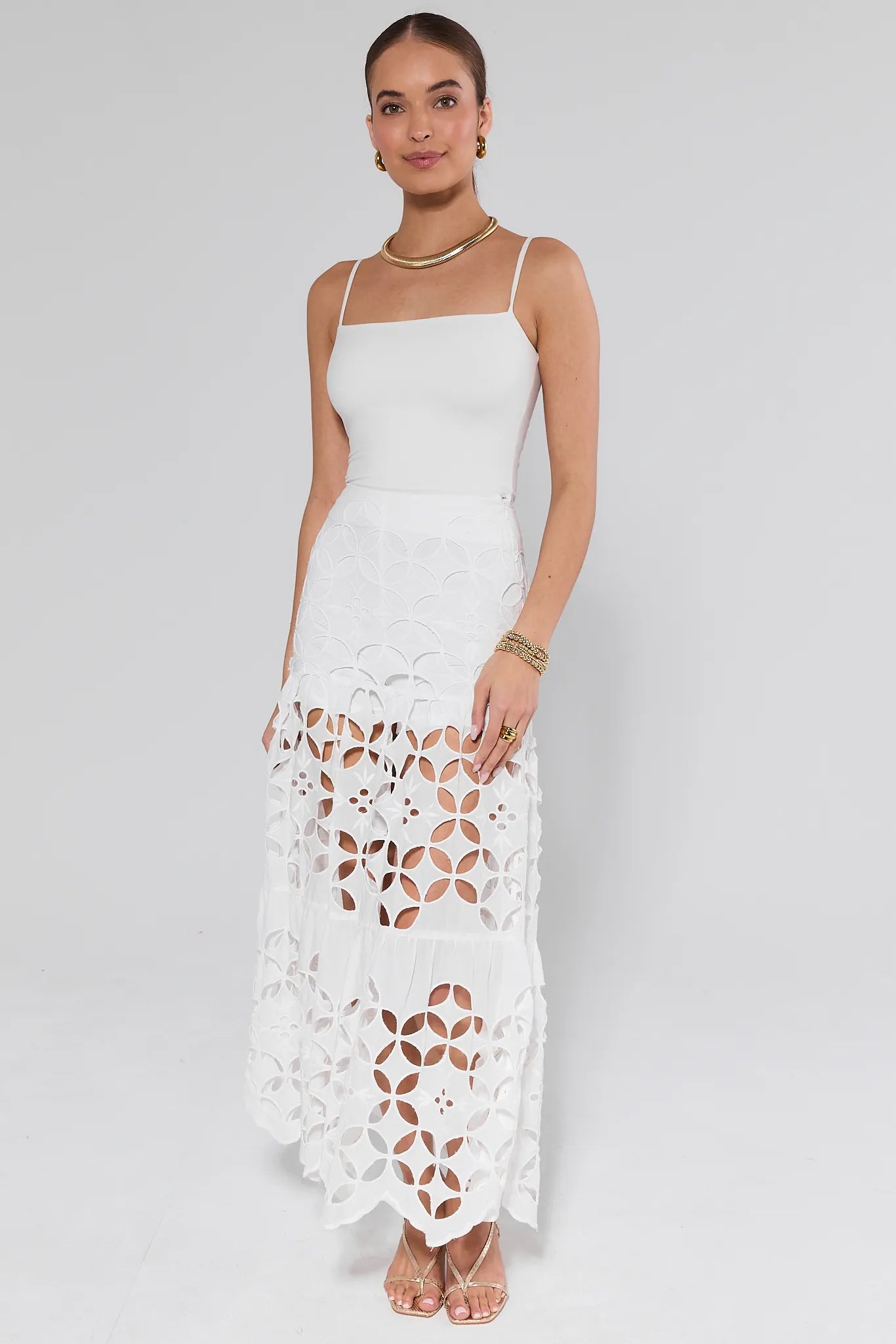Woman wearing a Cynthia White Cutout Maxi Skirt with a white tank top on a plain background