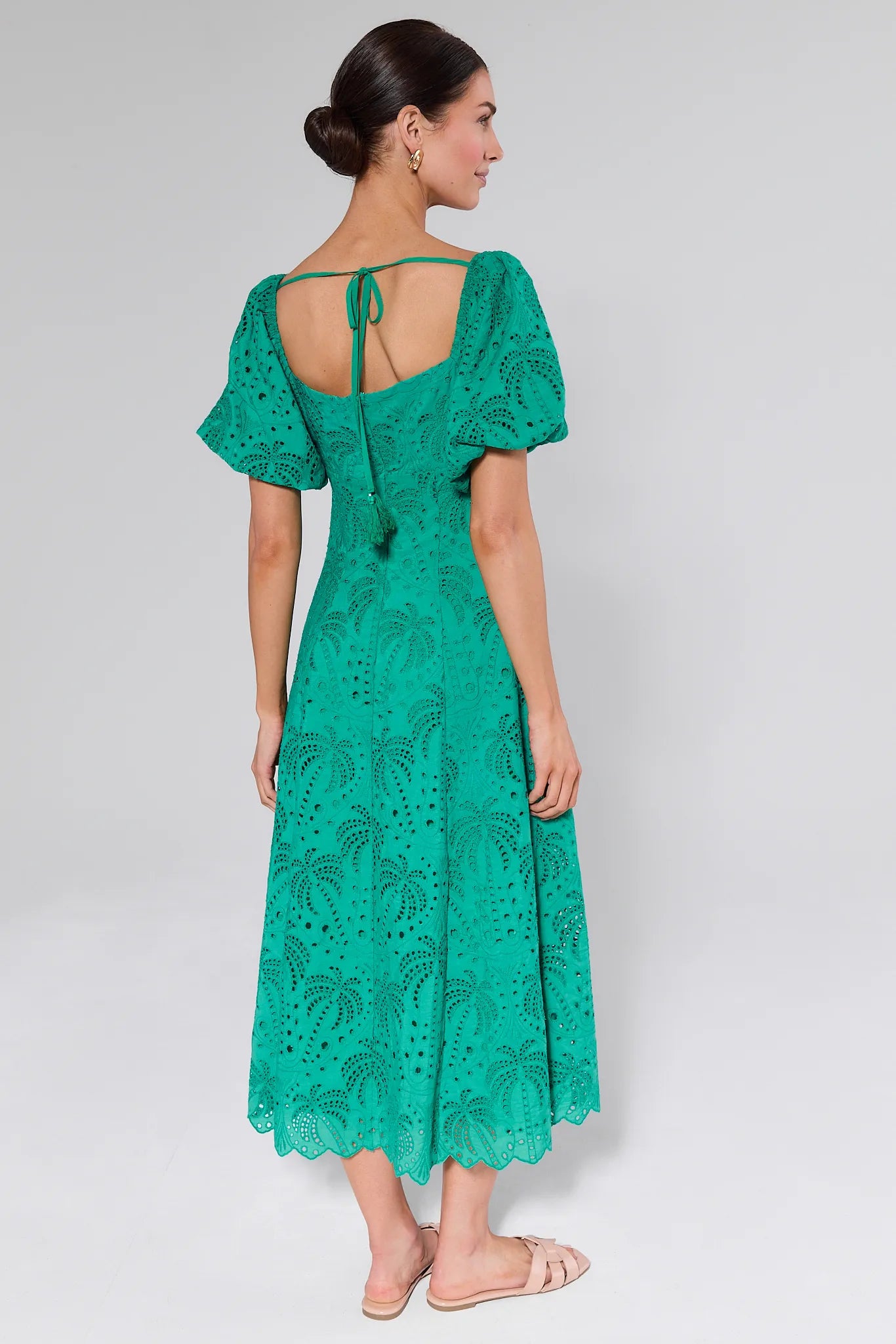 Woman wearing a Sydney Green Eyelet Dress with tassel detail on a plain background