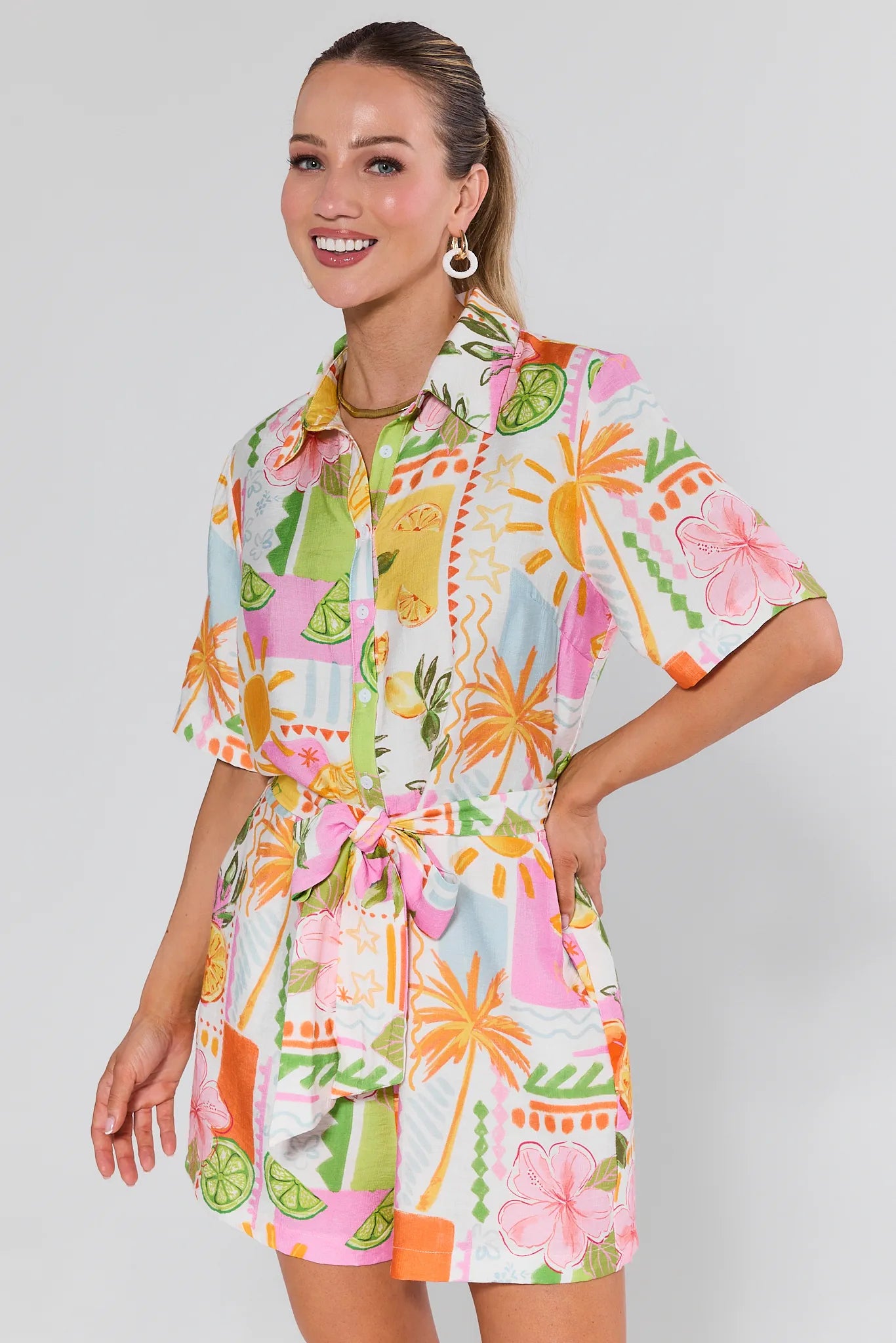 Woman wearing a colorful Saylor Printed Button Up Romper on a plain background