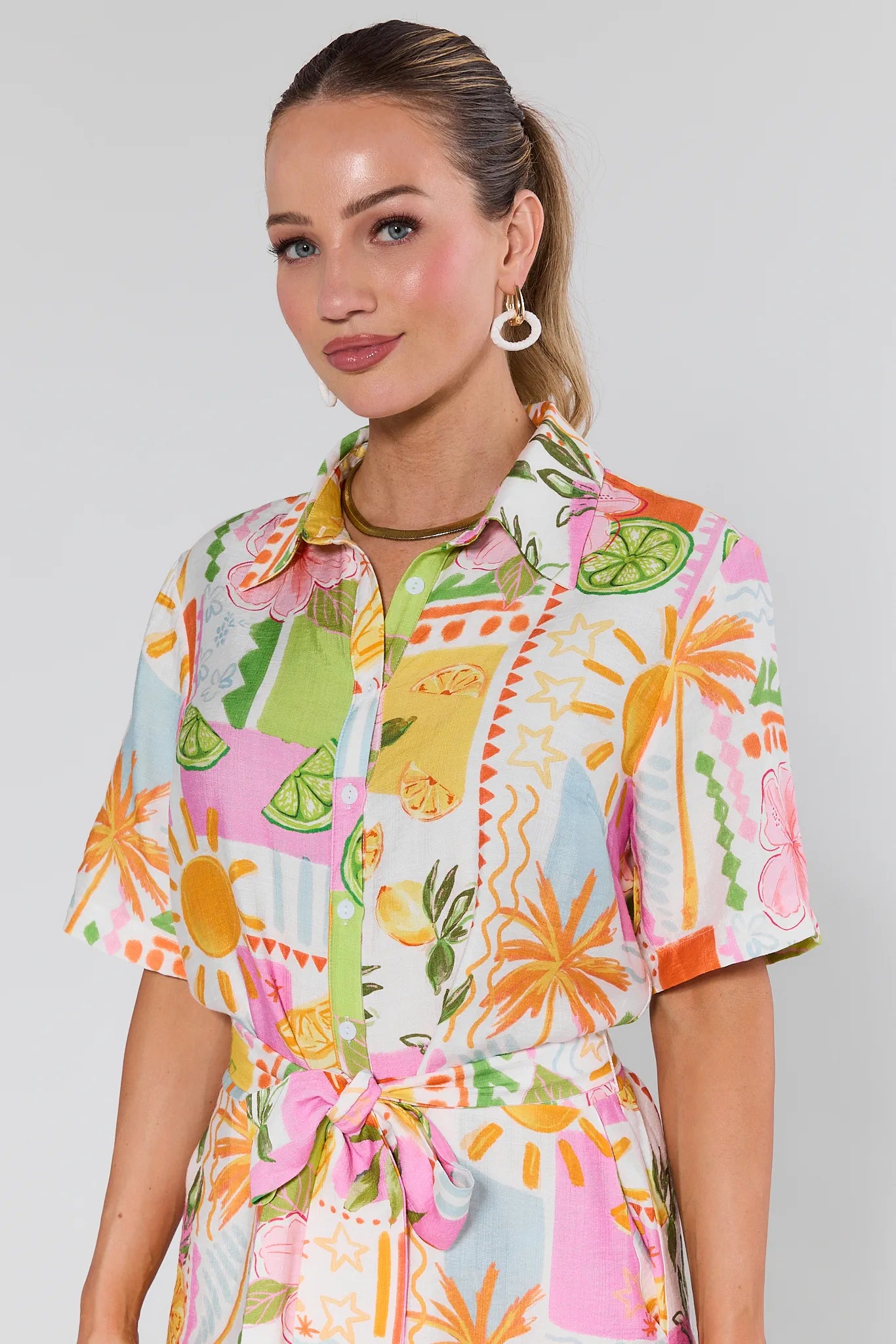Woman wearing a colorful Saylor Printed Button Up Romper on a plain background