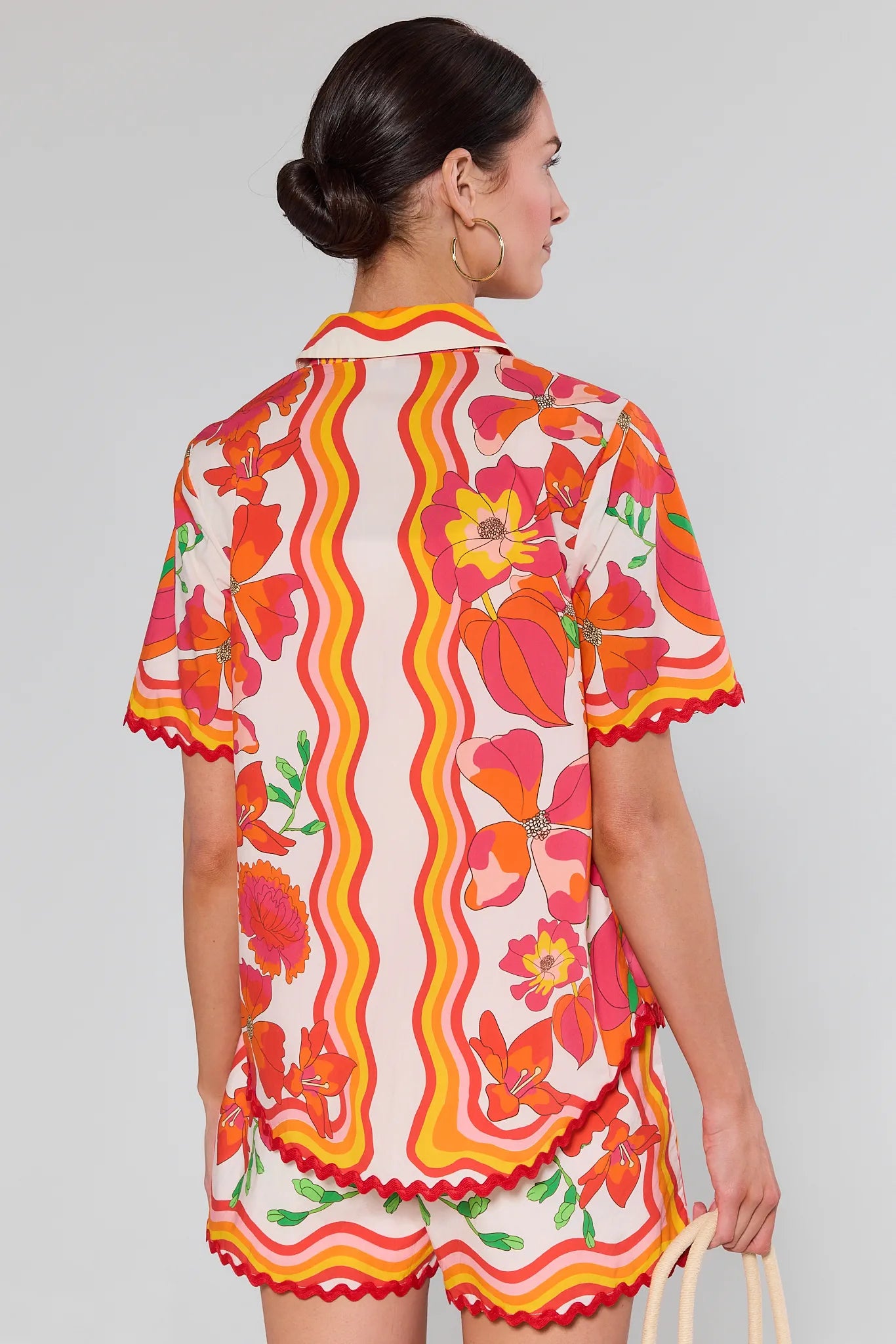 Woman wearing a Melissa Orange Printed Button Up Top with a white background