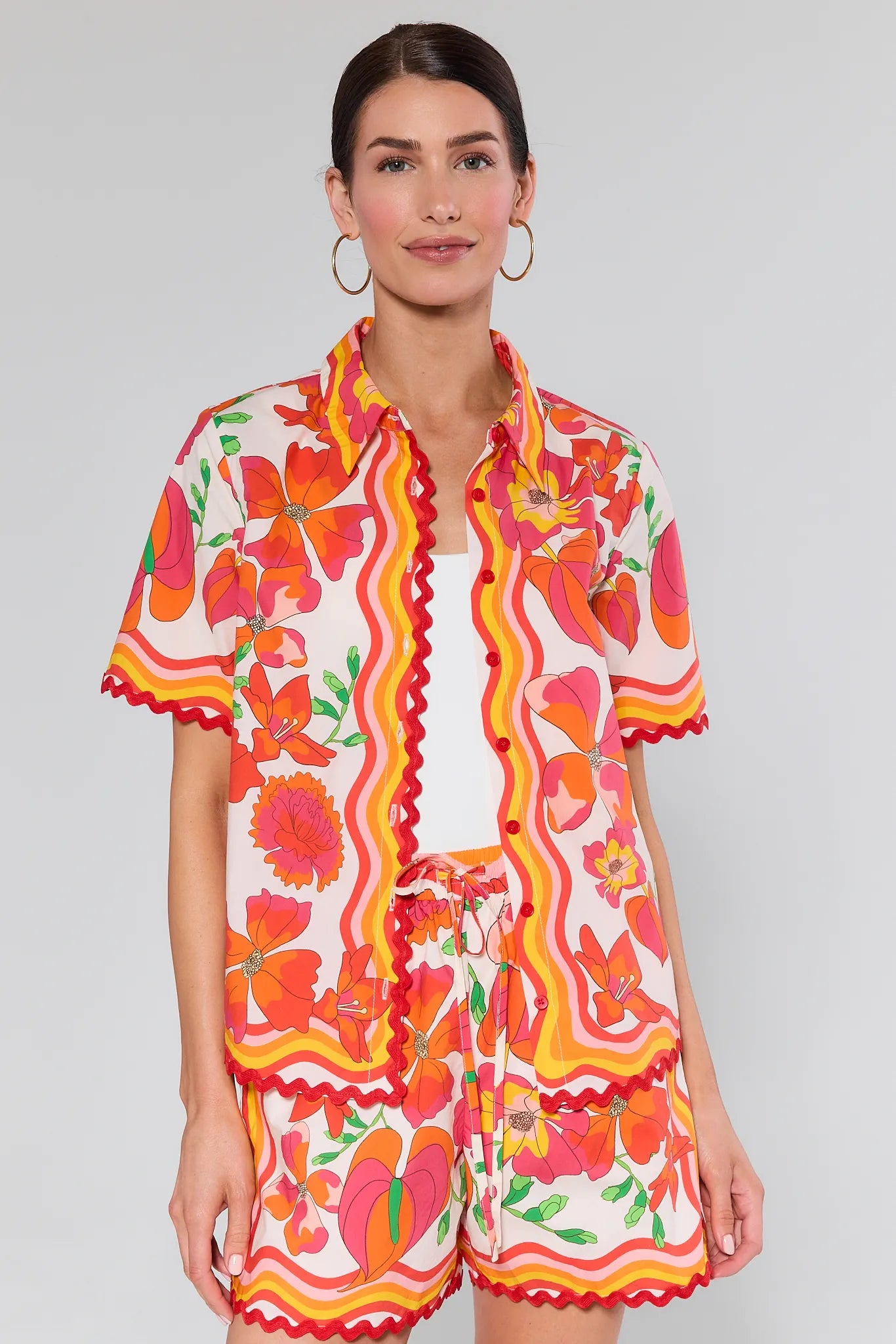 Woman wearing a Melissa Orange Printed Button Up Top with a white background
