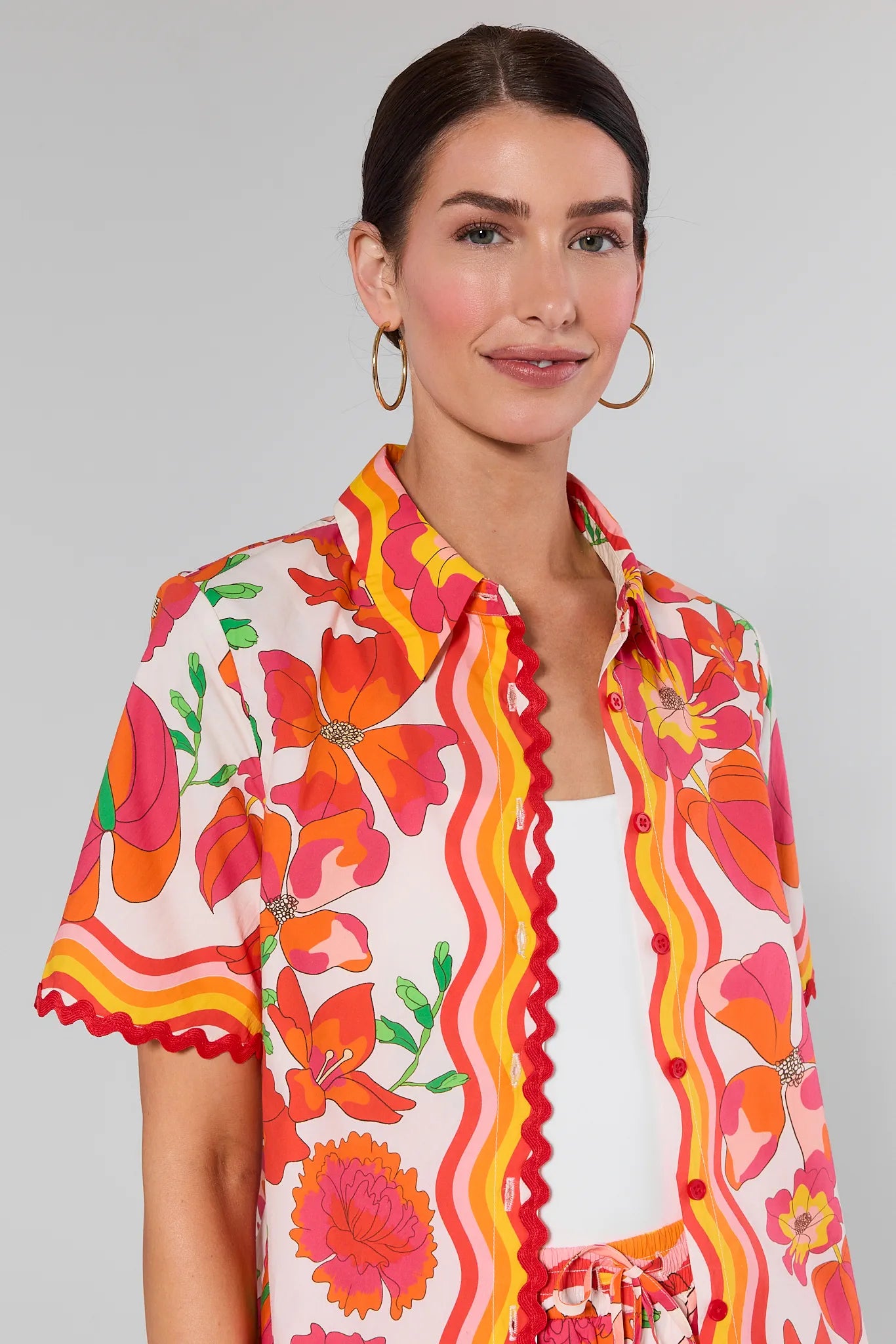 Woman wearing a Melissa Orange Printed Button Up Top with a white background