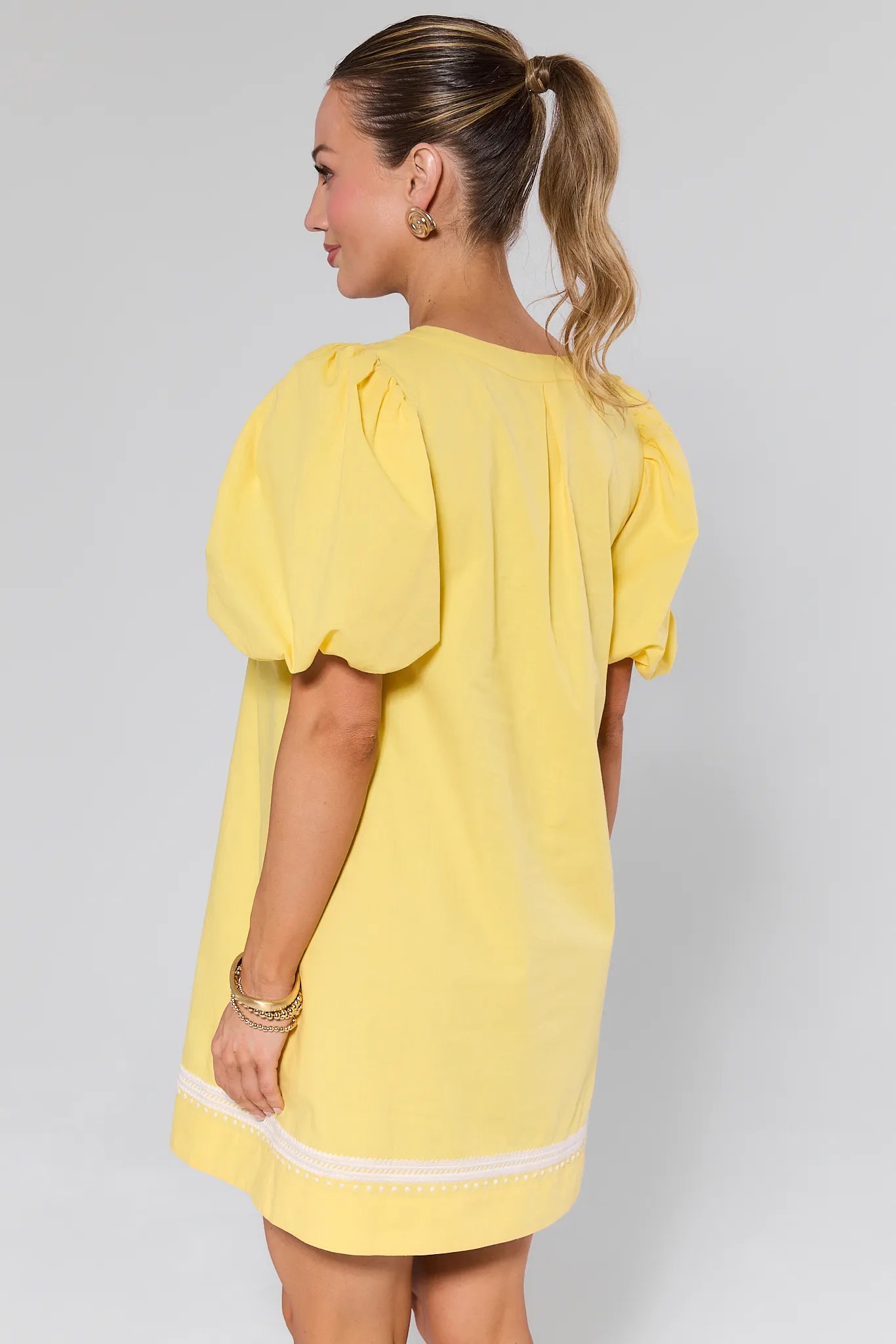 Woman wearing a yellow dress with white embroidery on a plain background Roxanne Dress Yellow