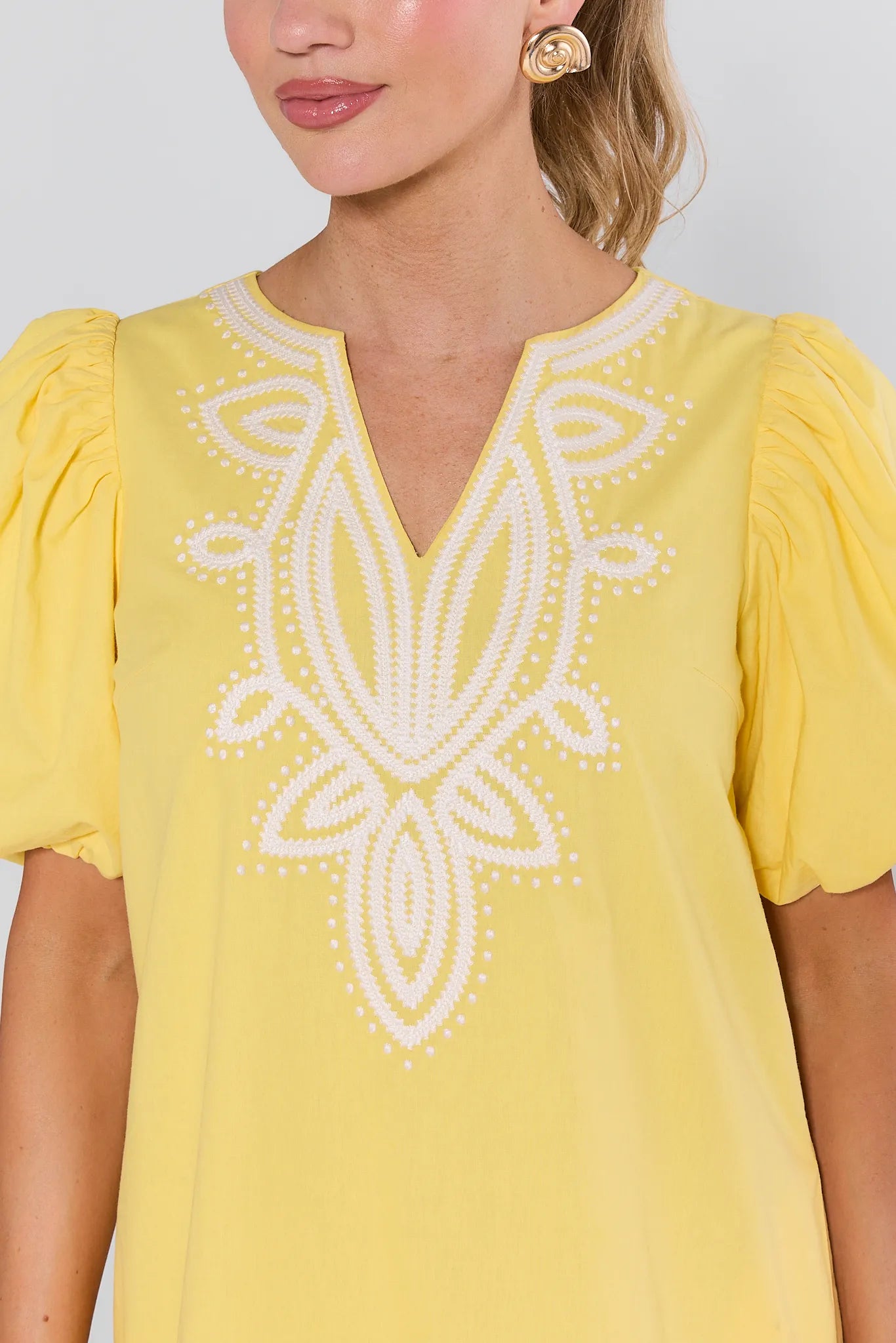 Woman wearing a yellow dress with white embroidery on a plain background Roxanne Dress Yellow