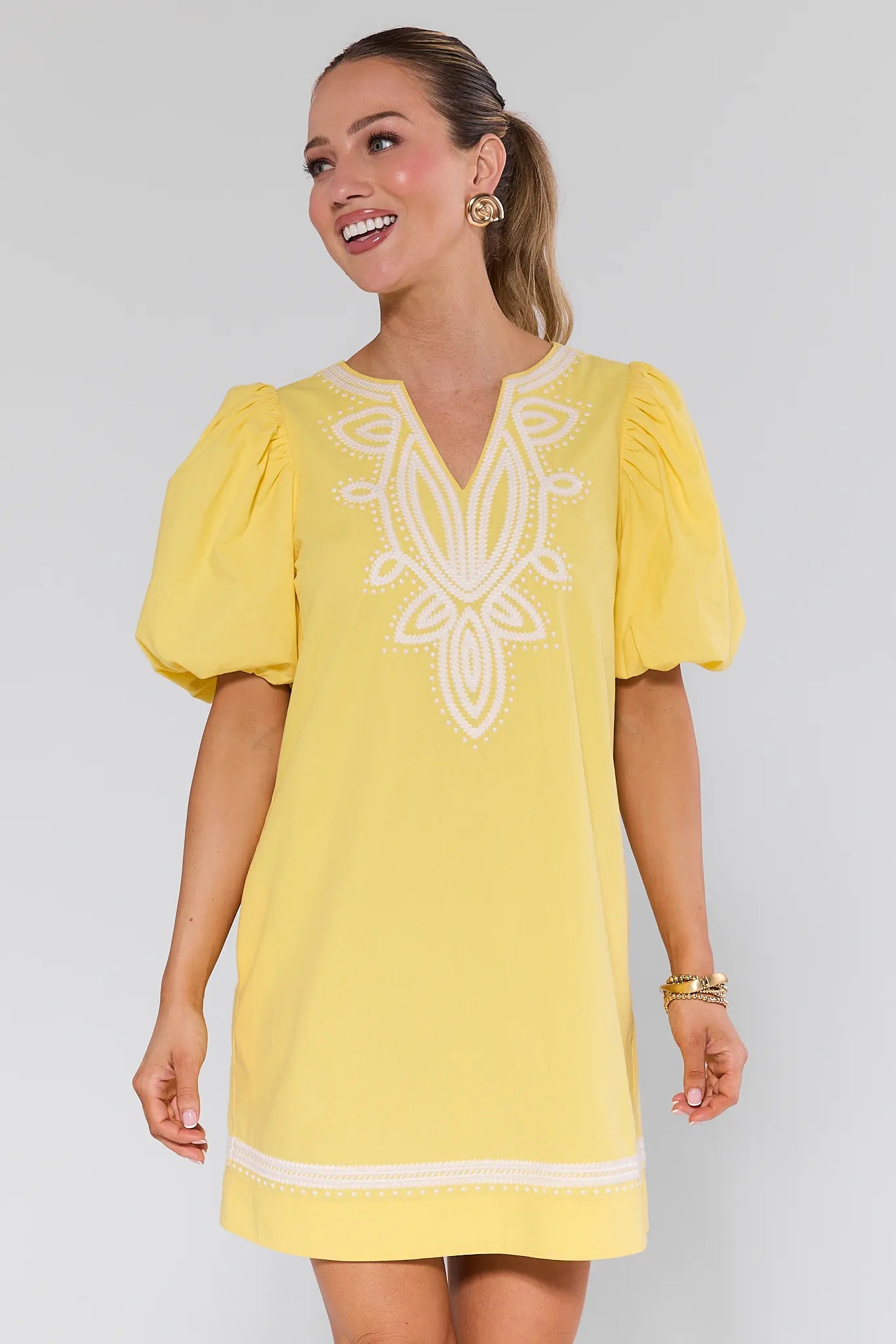 Woman wearing a yellow dress with white embroidery on a plain background Roxanne Dress Yellow