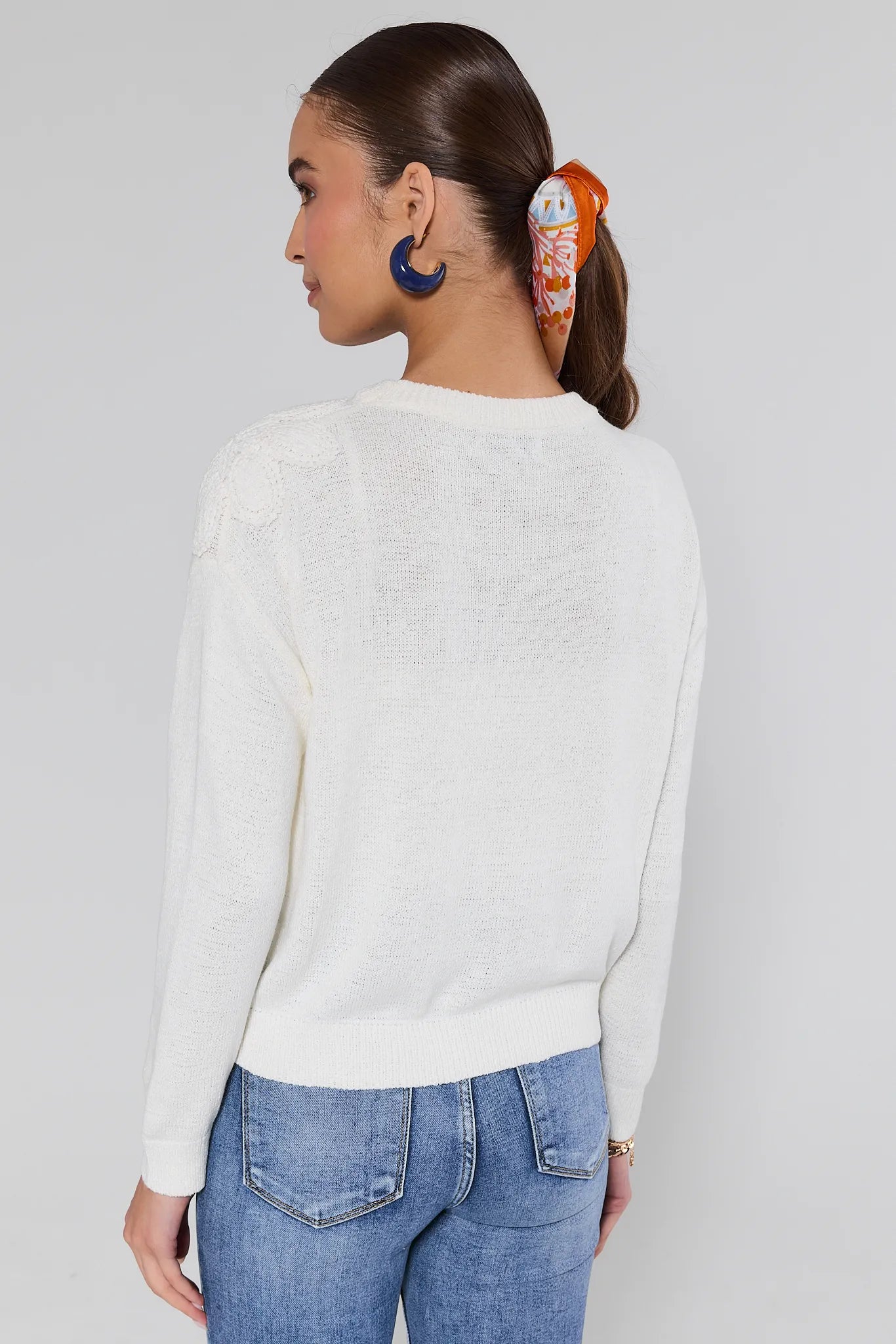 Woman wearing a Violet Cream Summer Sweater and blue jeans against a light gray background