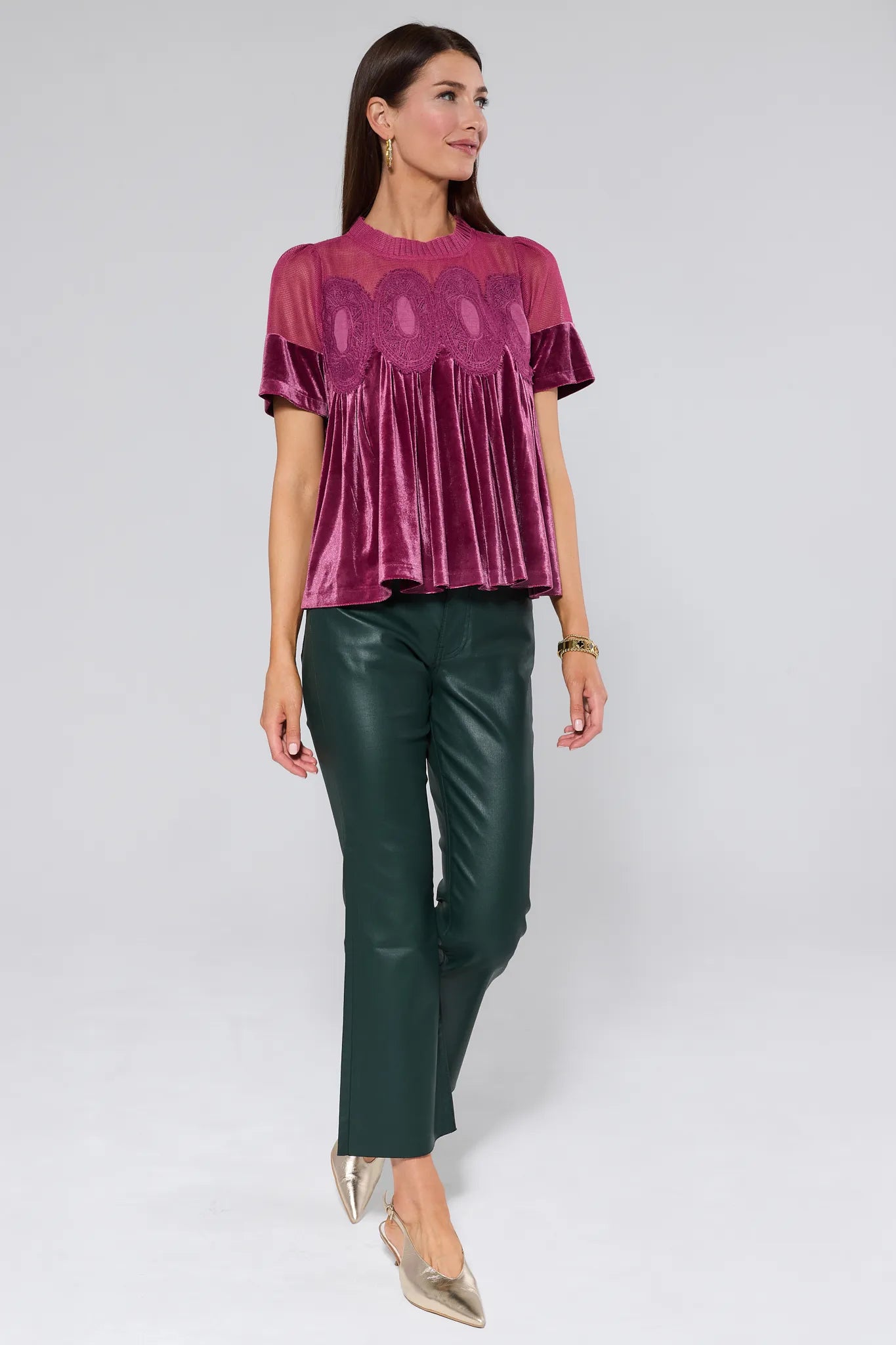 Woman wearing a burgundy gabrielle velvet top with lace details on a plain background