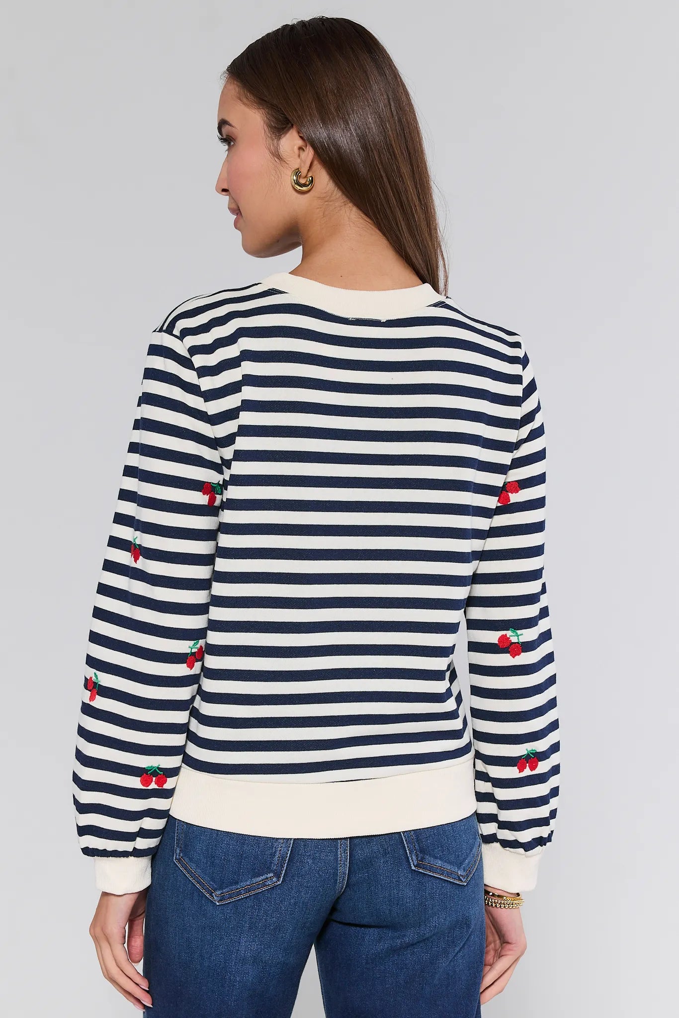 Woman wearing a navy and white striped Belle Sweatshirt with red accents on a plain background
