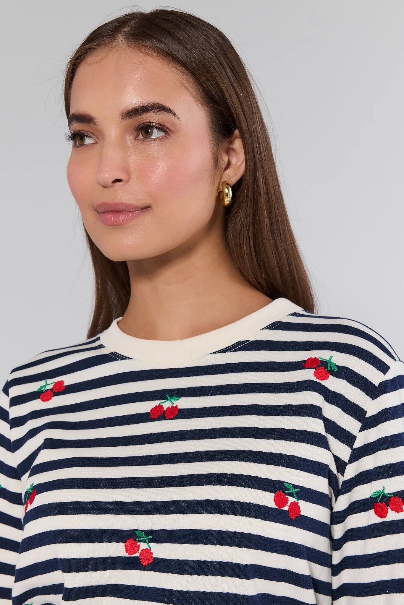 Woman wearing a navy and white striped Belle Sweatshirt with cherry designs on a plain background