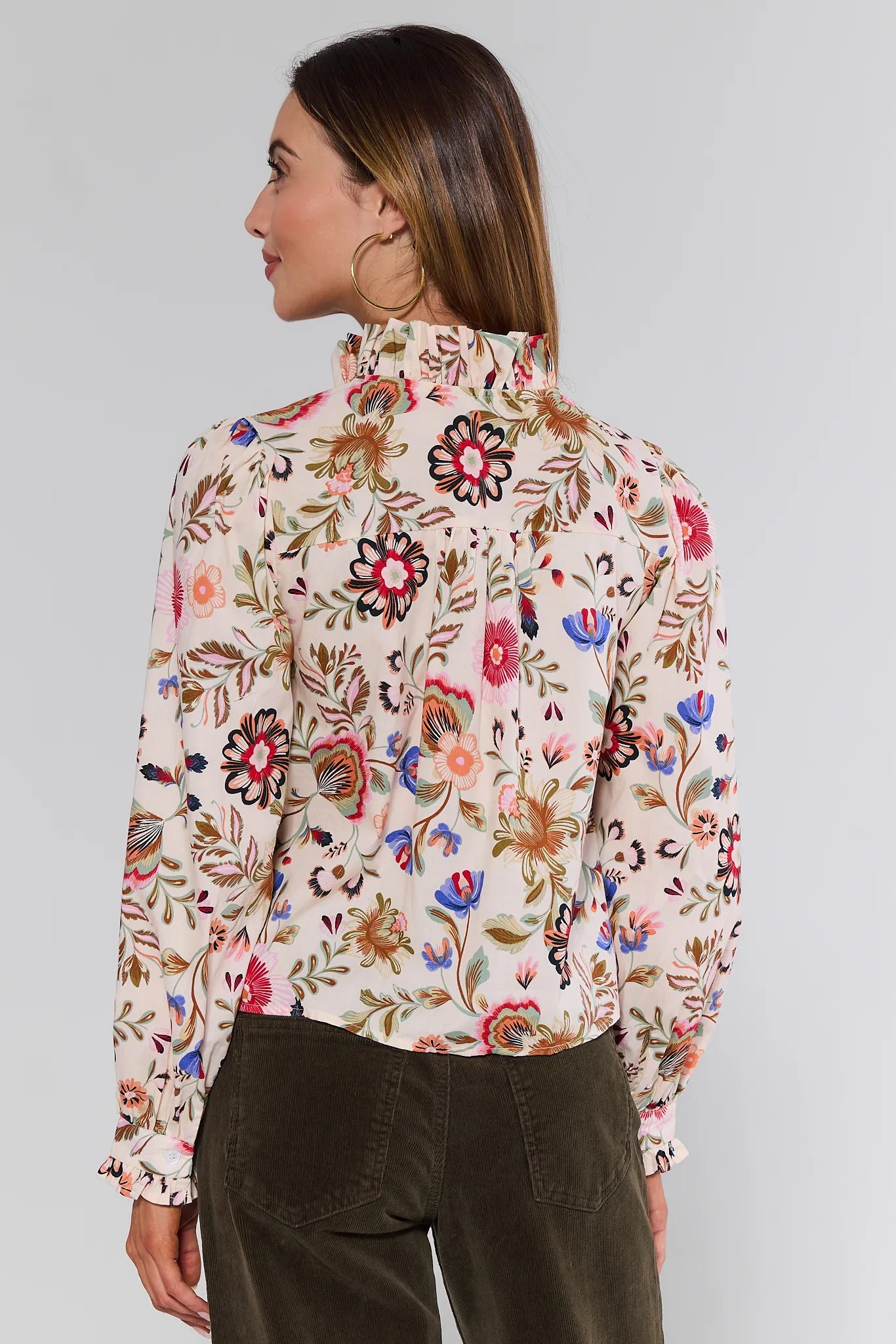 Woman wearing a floral Corinna Top with a plain background